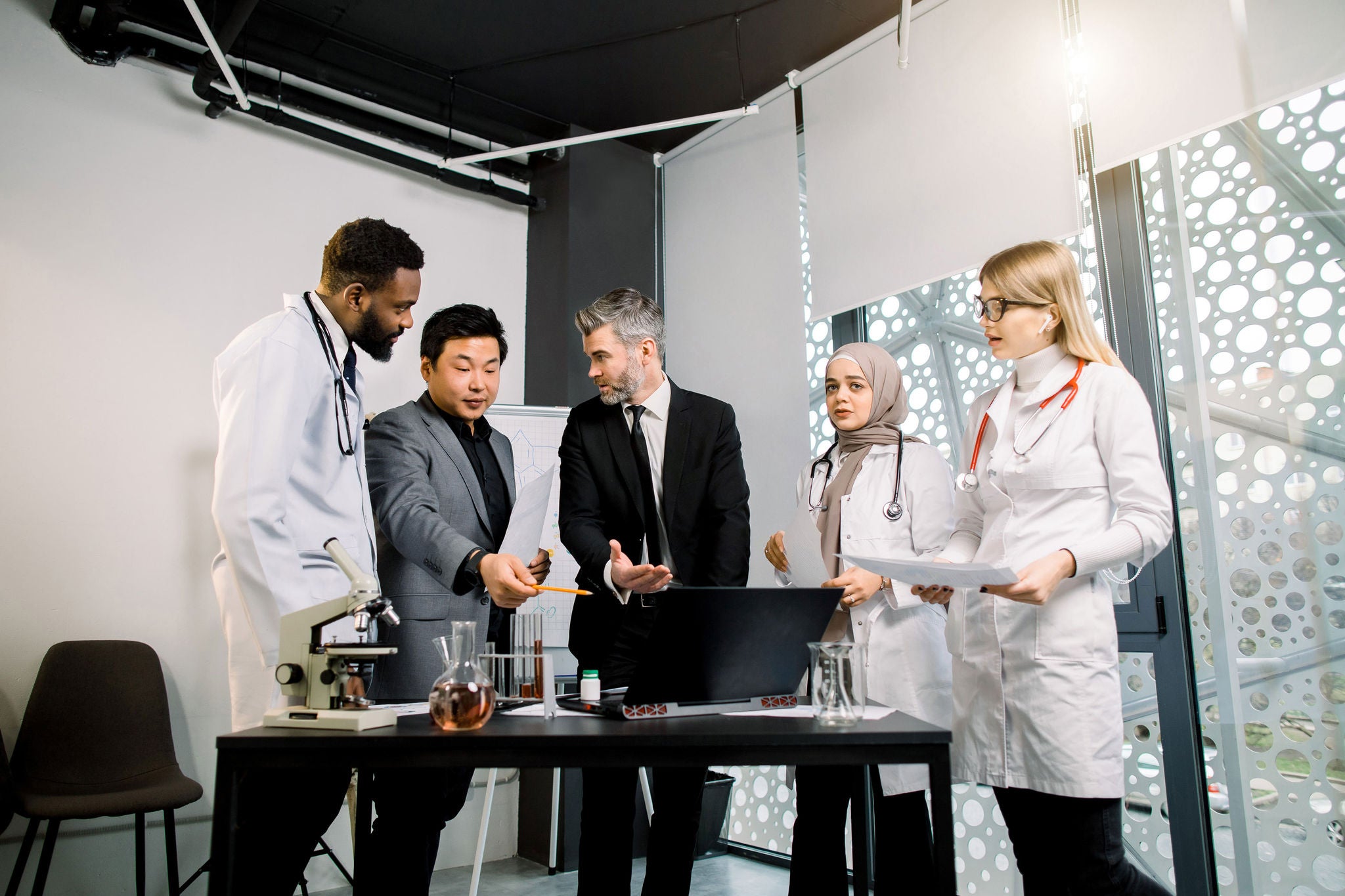 A businessman and his partner in discussion with three multiethnic doctors