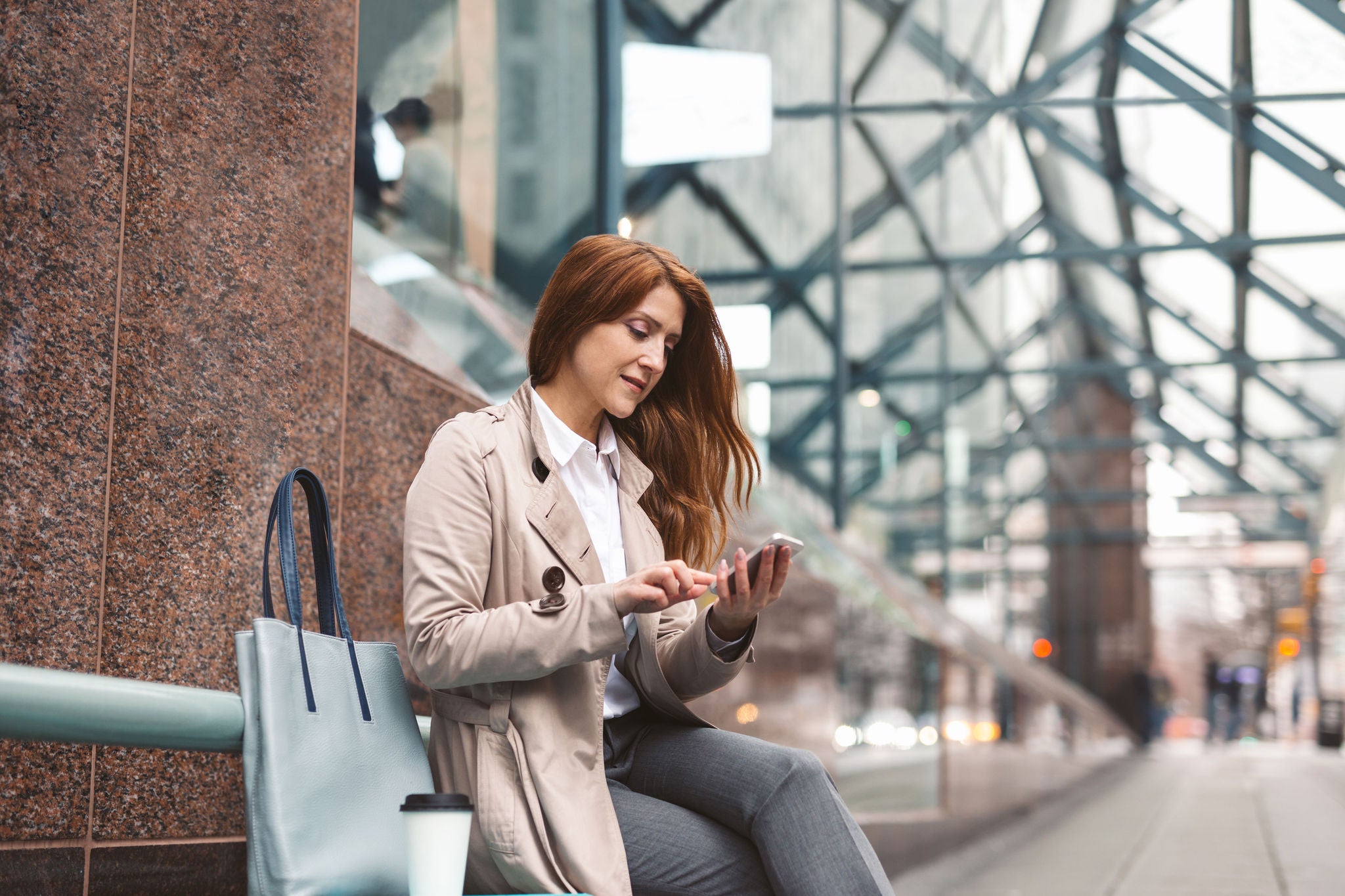 Business woman using smart phone on a train platform