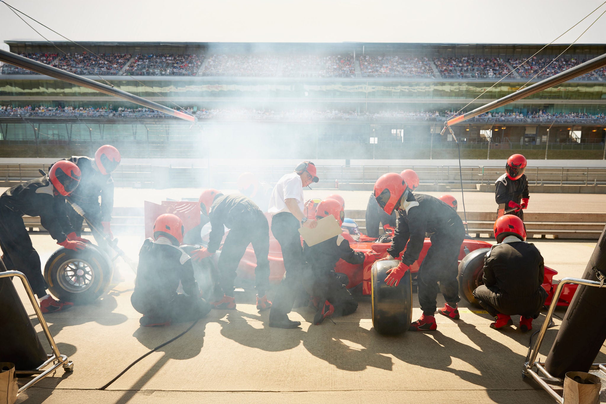 Pit crew replacing tires on formula one race car in pit lane