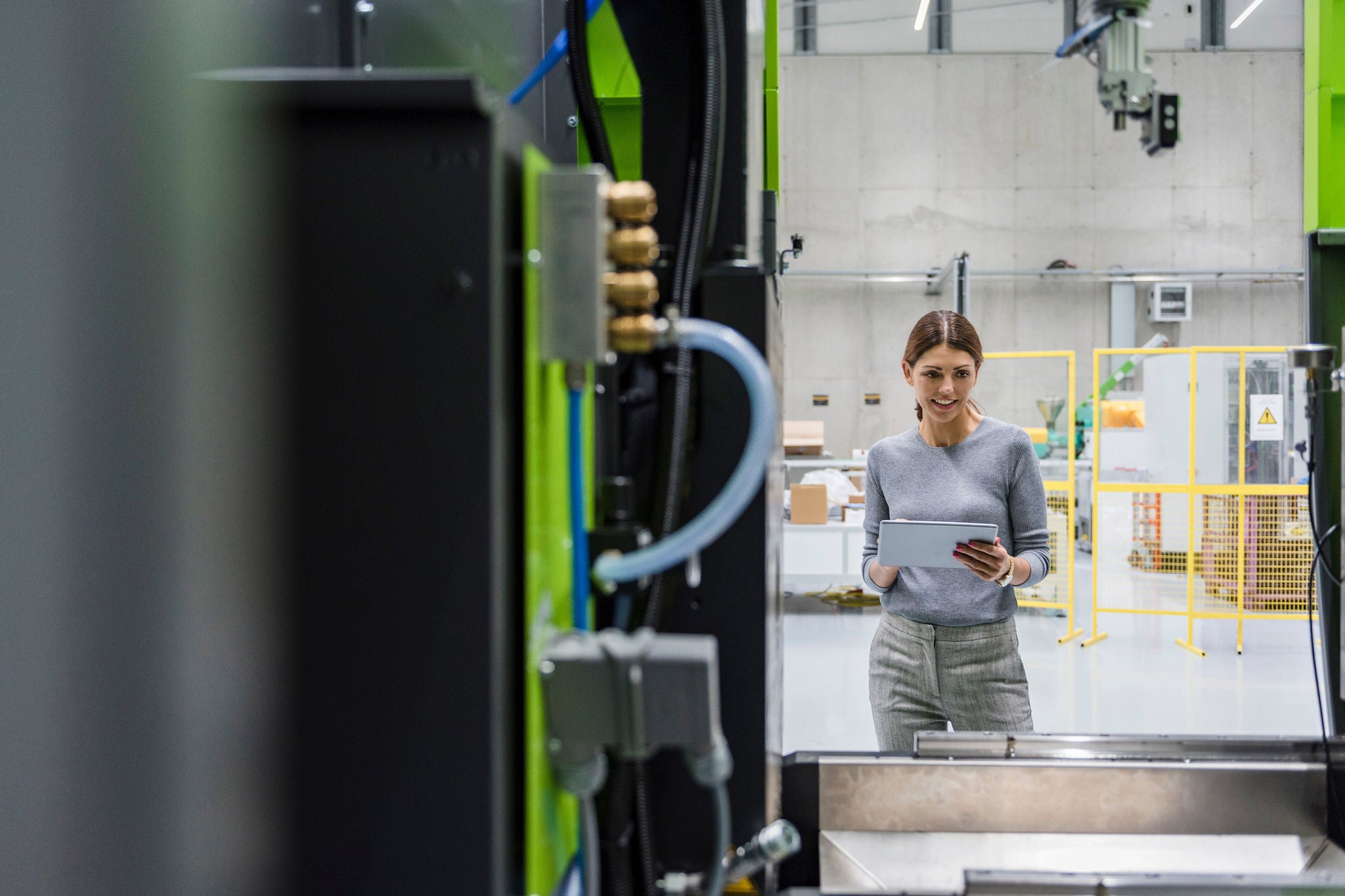 Businesswoman in high tech company controlling manufacturing machines, using digital tablet