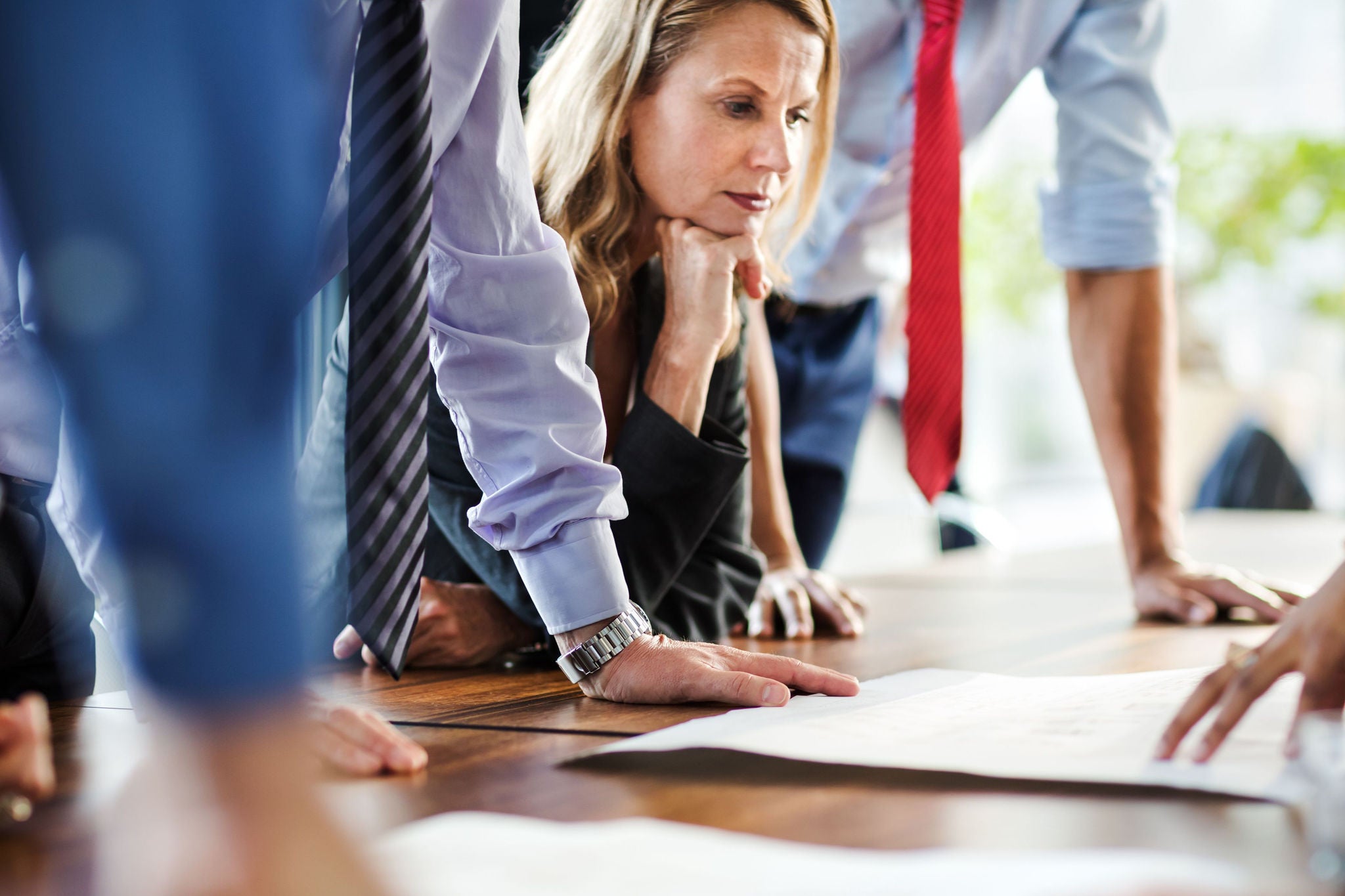 Mature Businesswoman during meeting listening to colleagues on a table.