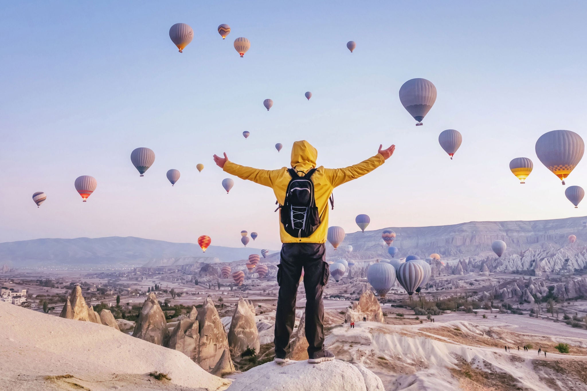 At dawn a tourist with a backpack on the background of soaring hot air balloons in Cappadocia, Turkey