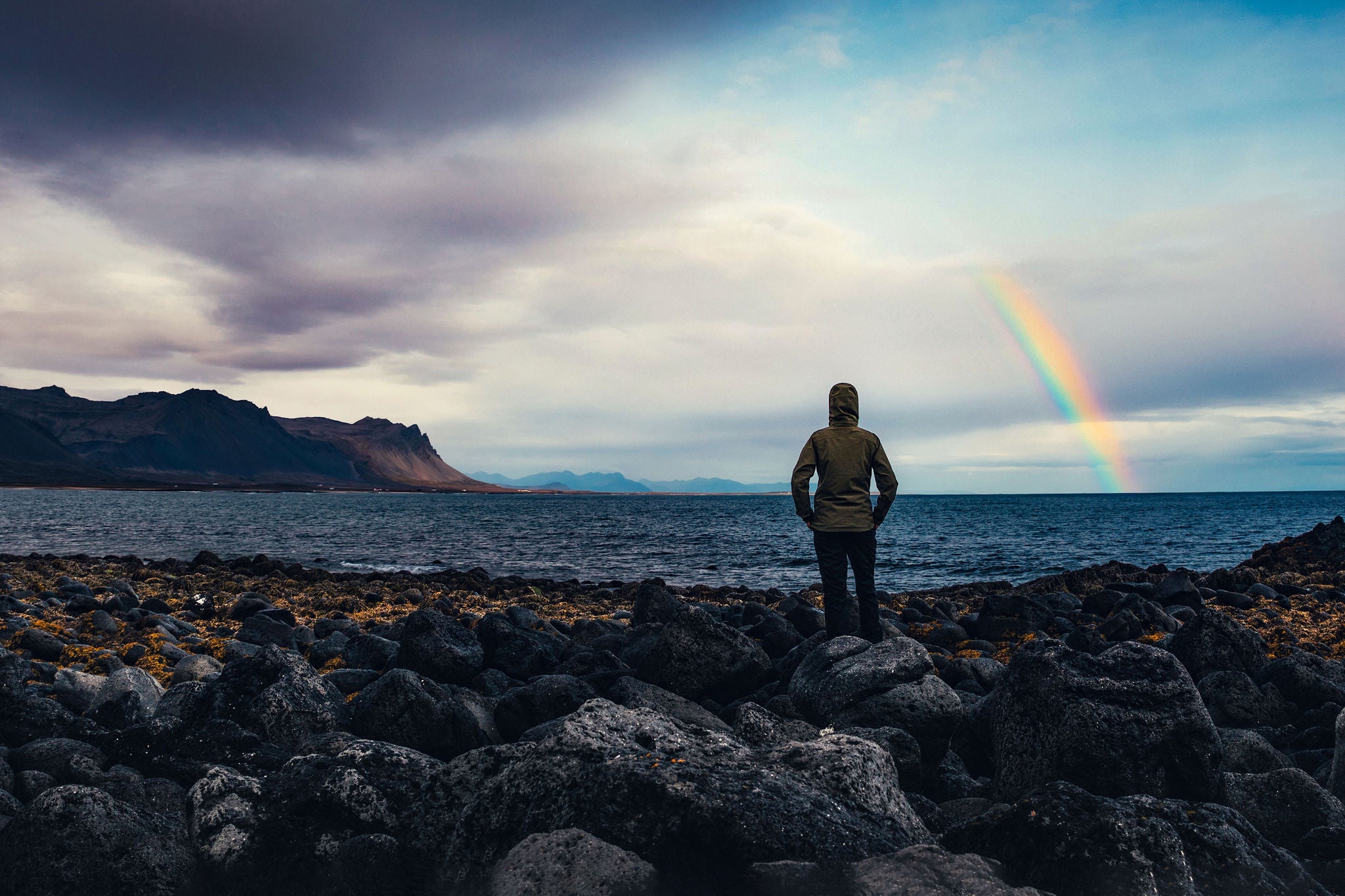 Woman watching rainbow over Icelandic landscape at Snaefellsnes peninsula (west parth of the island).