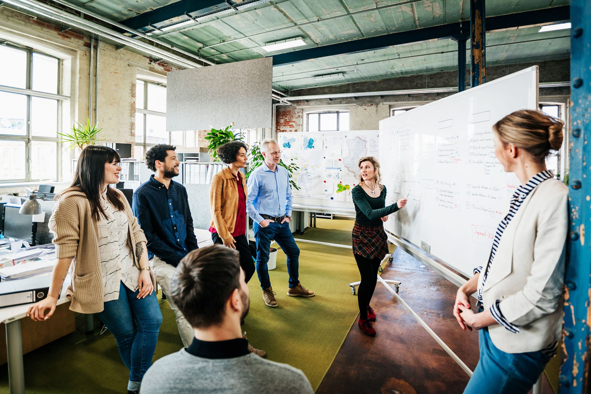 A team brainstorming and preparing for the day during a meeting at the office together.