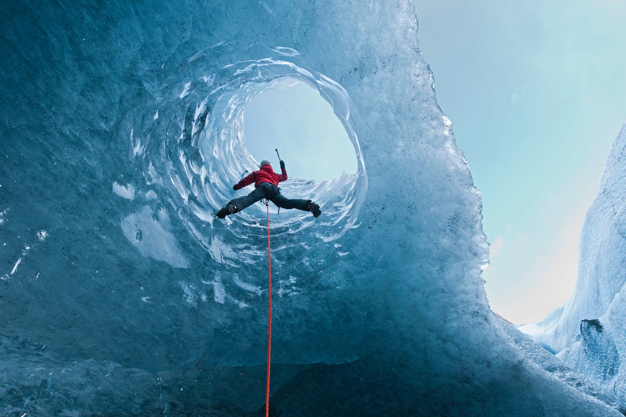 Woman climbing out of glacier cave