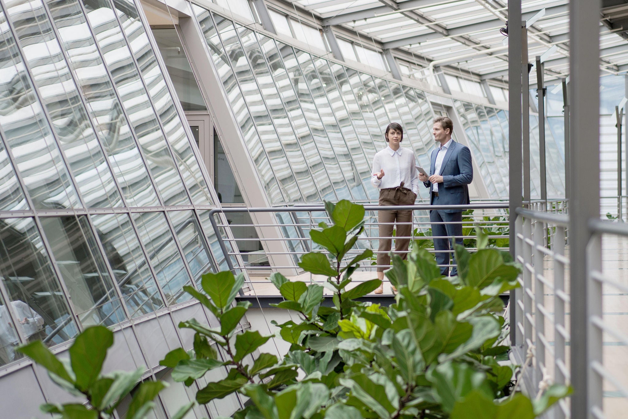 Woman and man talking at walkway in office building