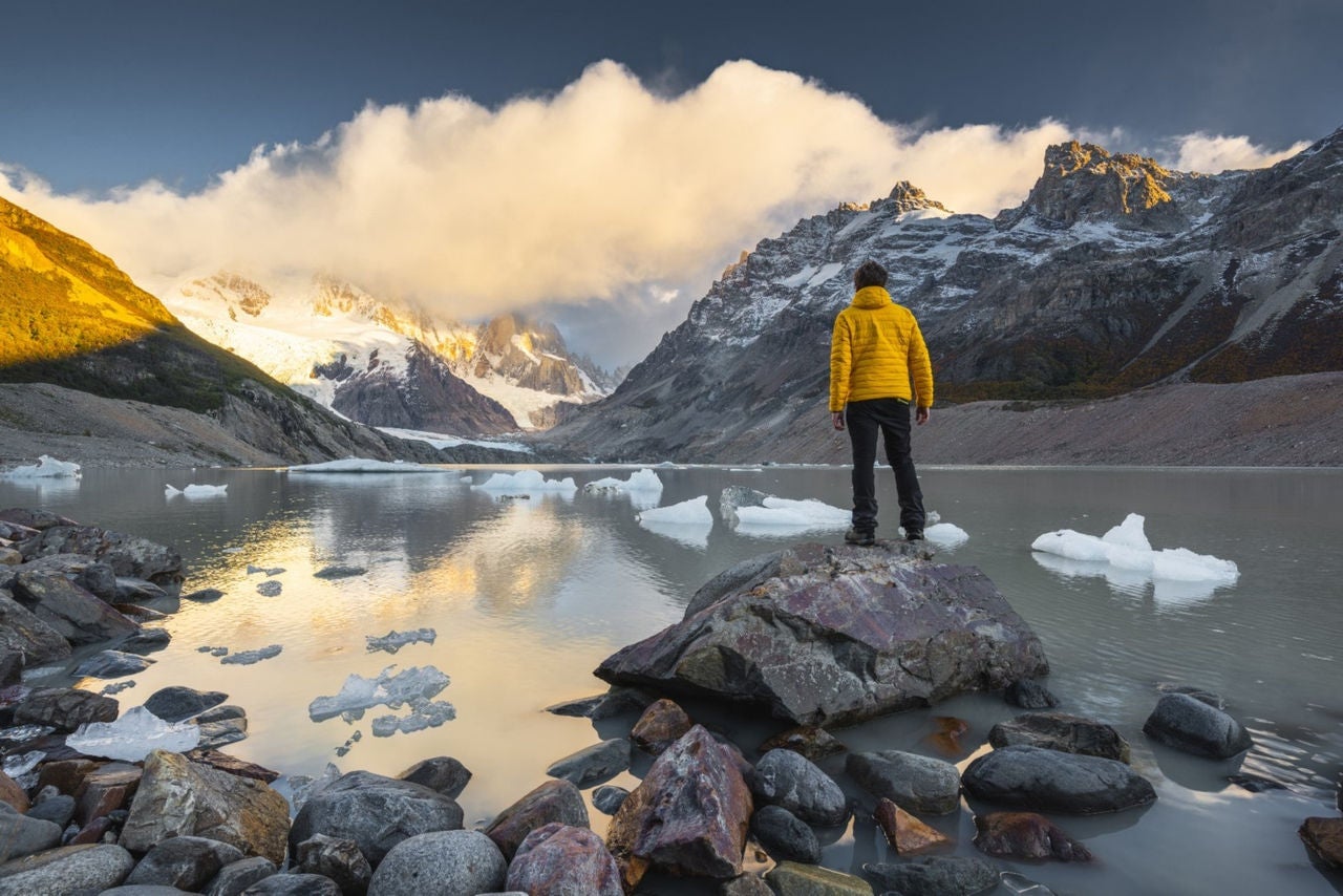 A person is standing on rock infront of lake