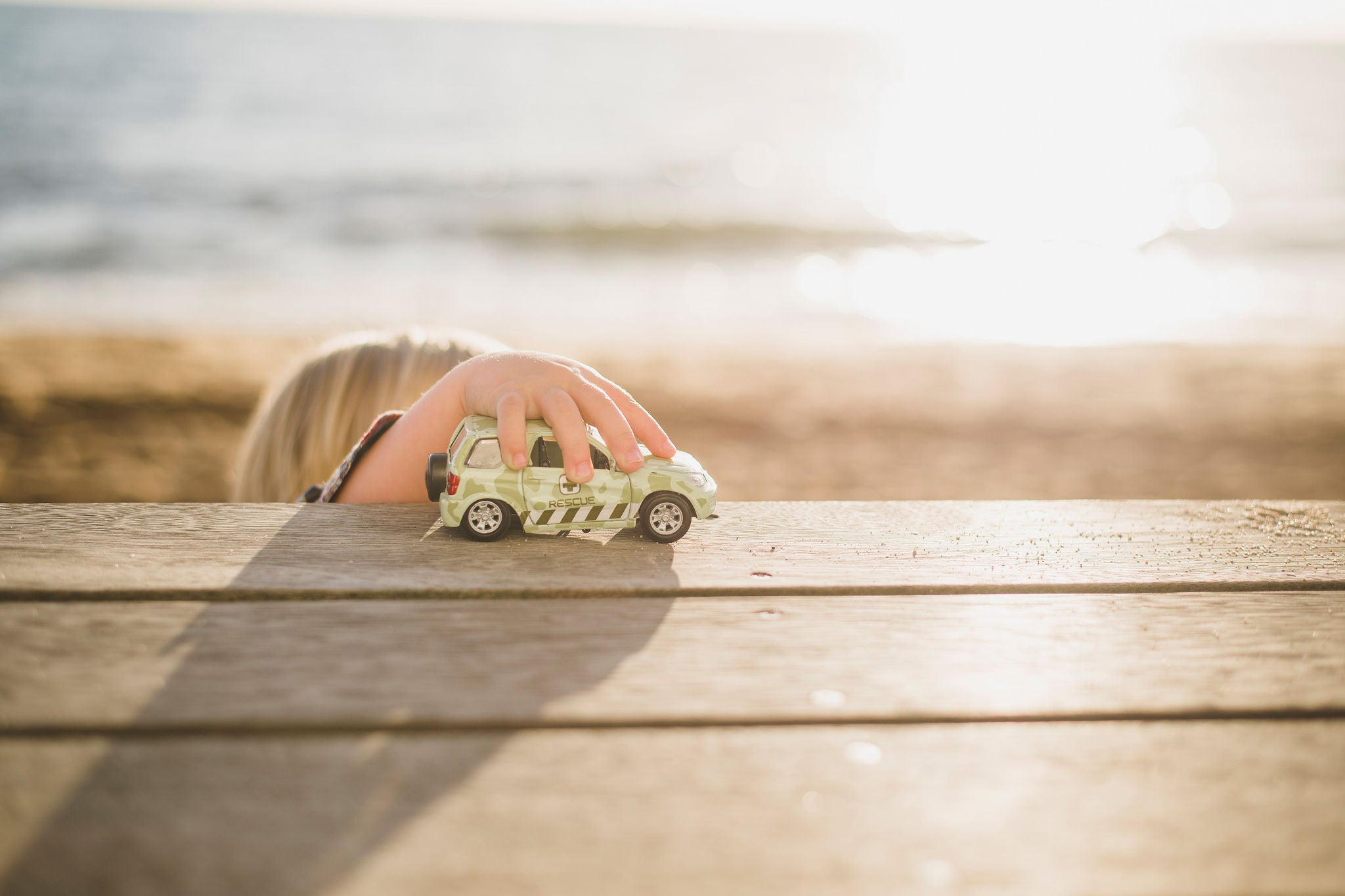 Jongen speelt met speelgoedauto op houten plank