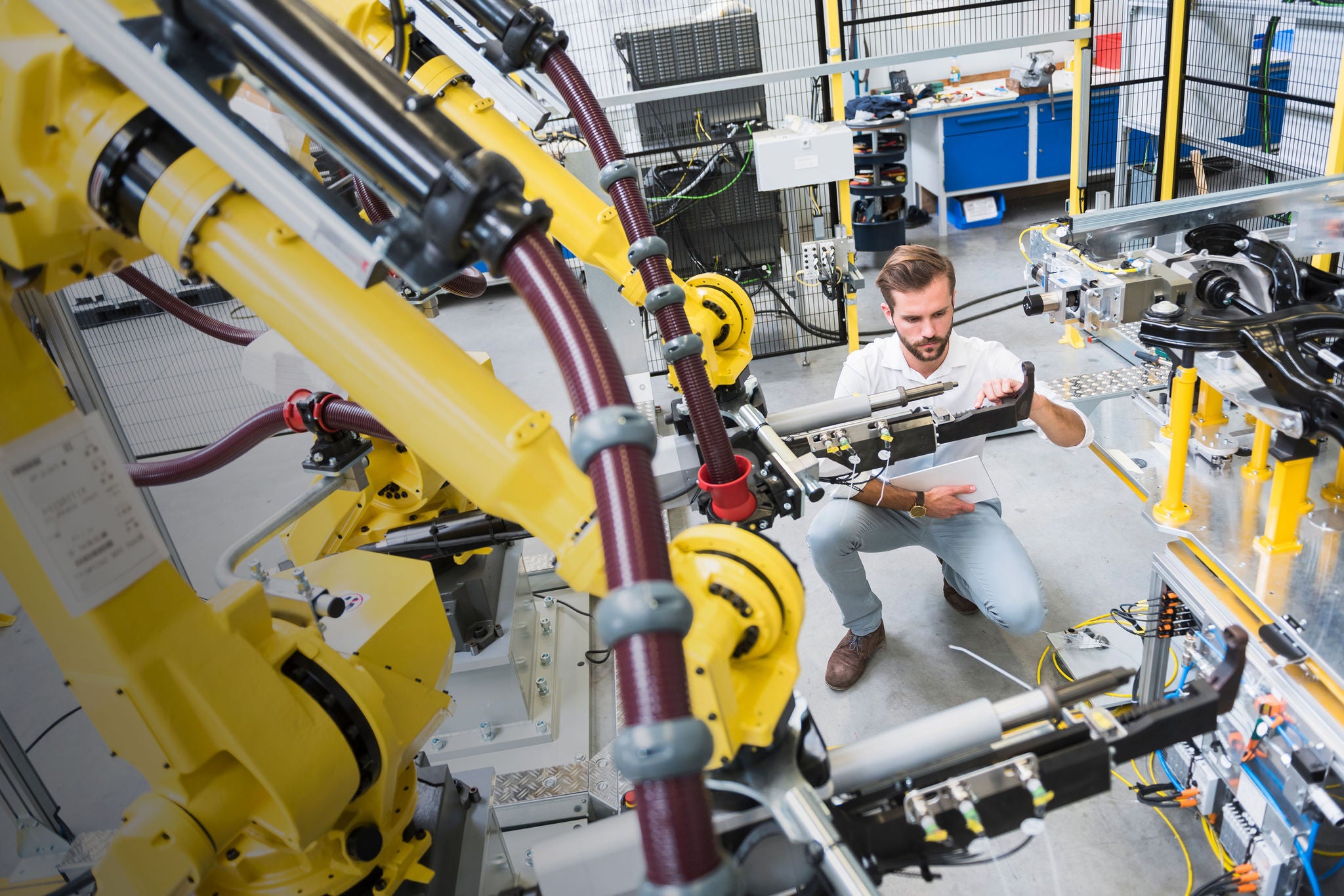 engineer crouching while examining computer-aided machinery