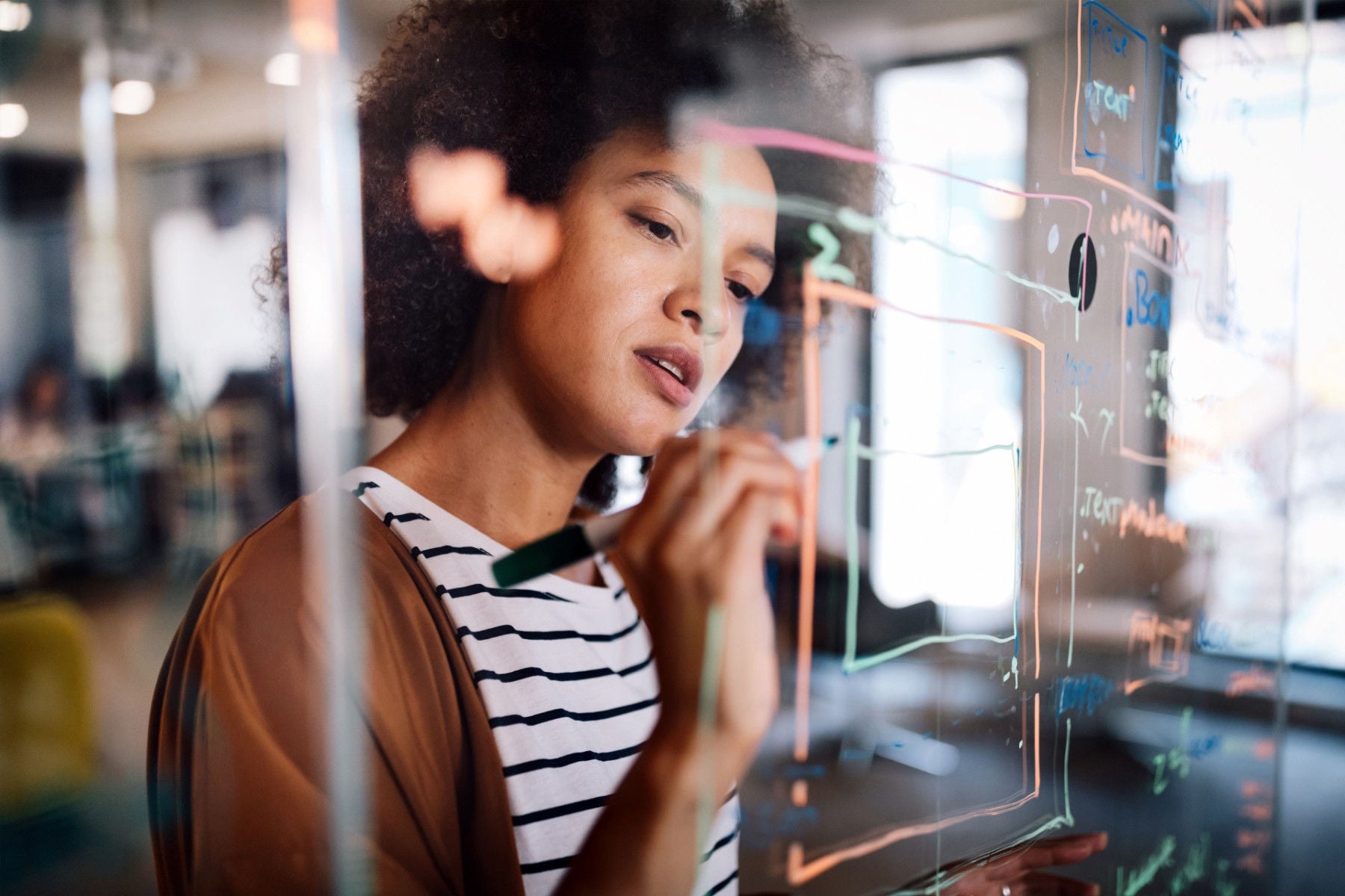 Woman working and writing on glass board in office