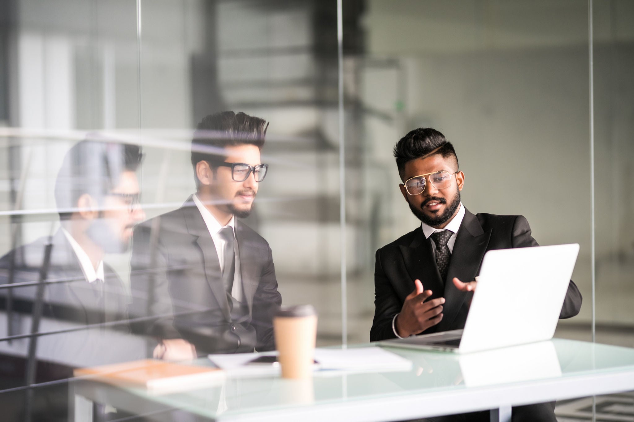 Three indian businessmen working together talking collaborate on laptop in office. Three Male business team discuss online project presentation corporate strategy with computer at meeting use laptop