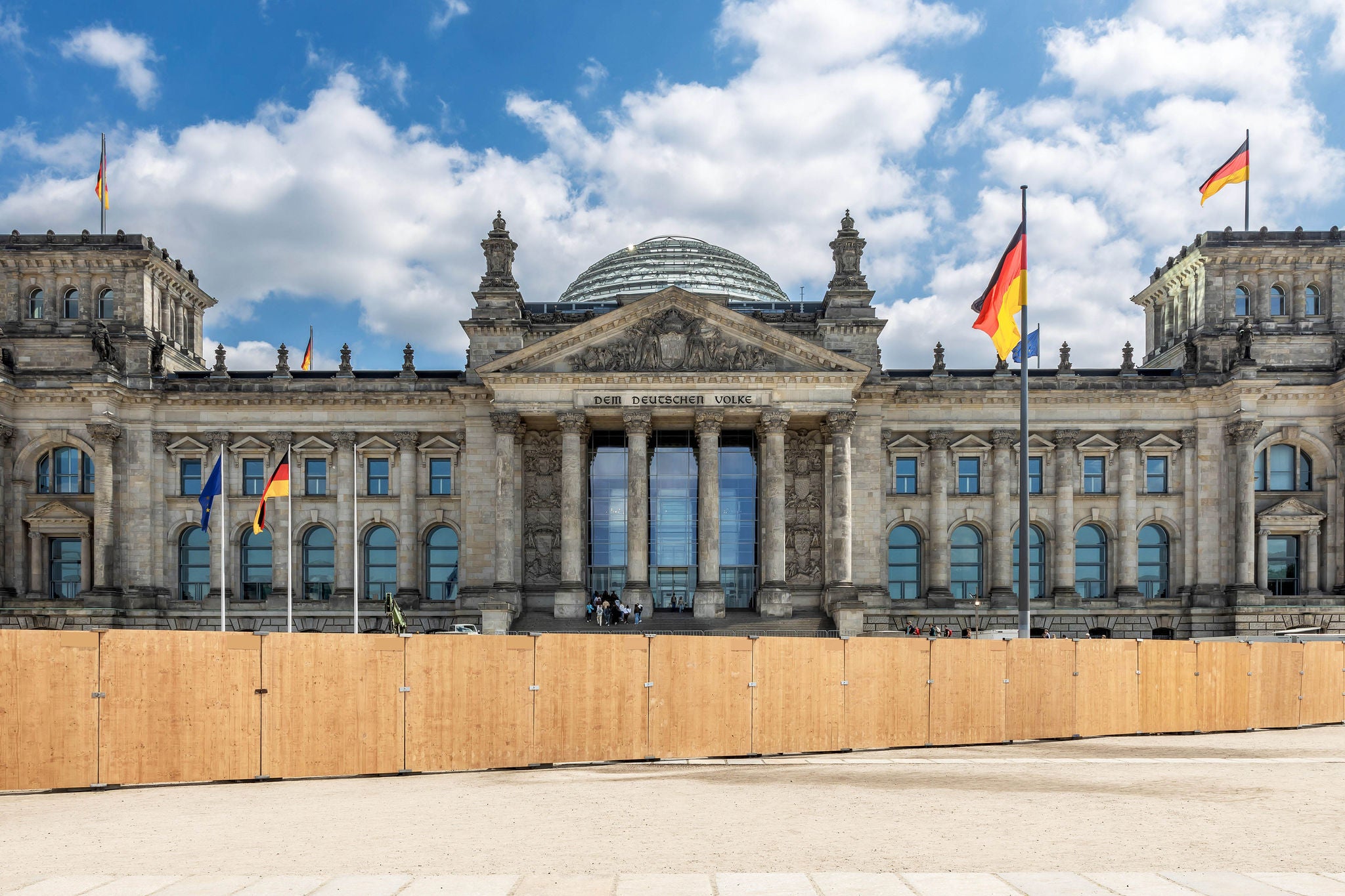 Baustelle vor dem Berliner Reichstagsgebaeude bei sonnigem Wetter und blauen Himmel mit einer wehenden Deutschlandflagge