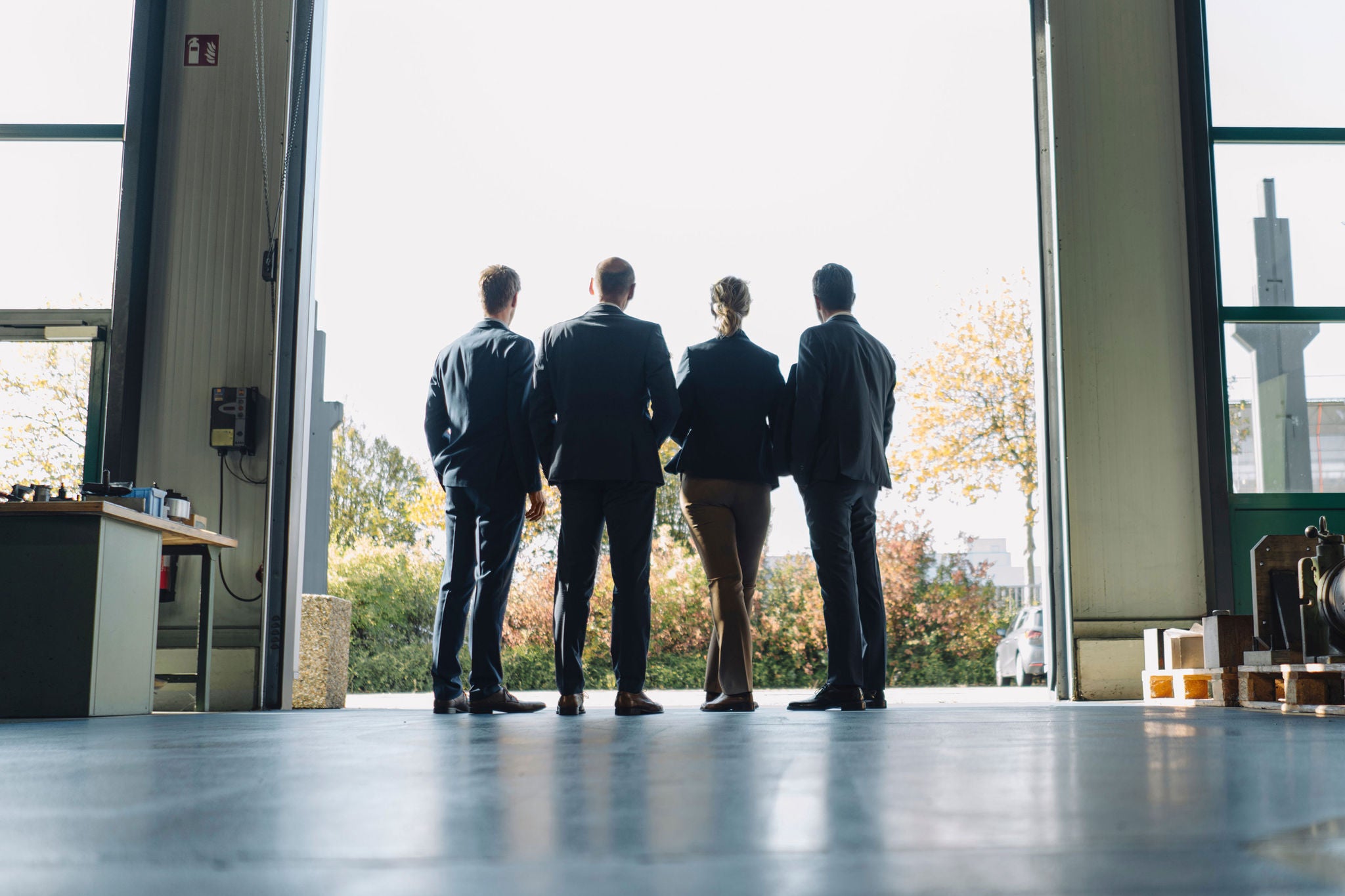 Rear view of business team standing at factory gate