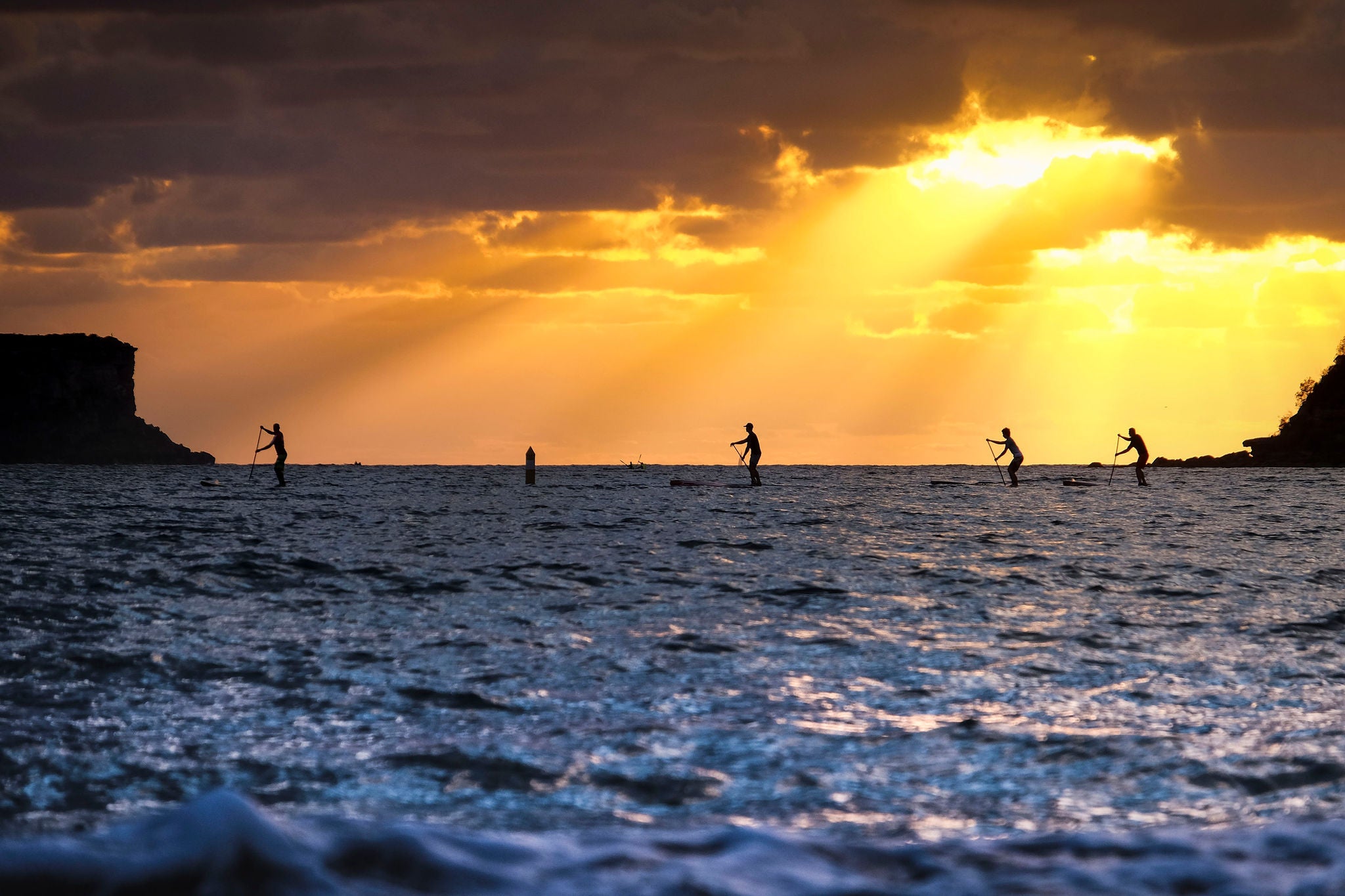 ocean paddleboarders silhouetted against afternoon