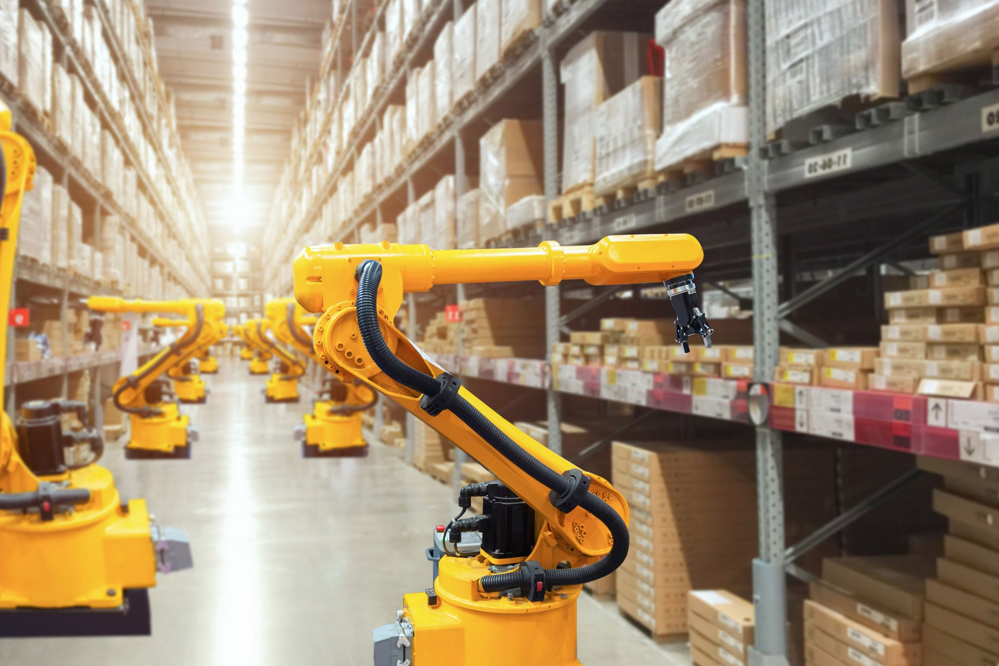 Automatic robot mechanical arm is working in temporary storage in a distribution warehouse. 
