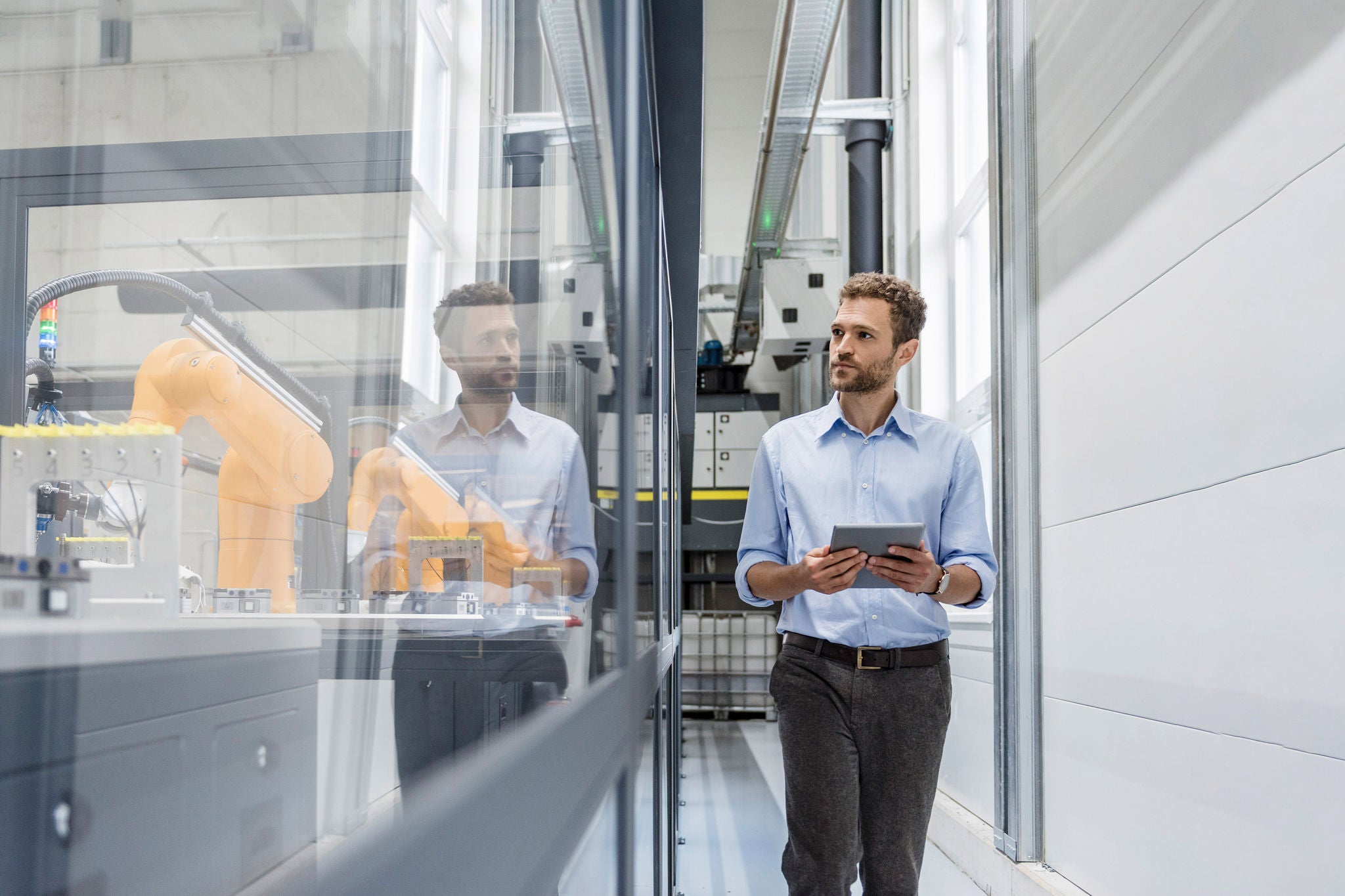 Businessman checking robots with digital tablet in high tech company