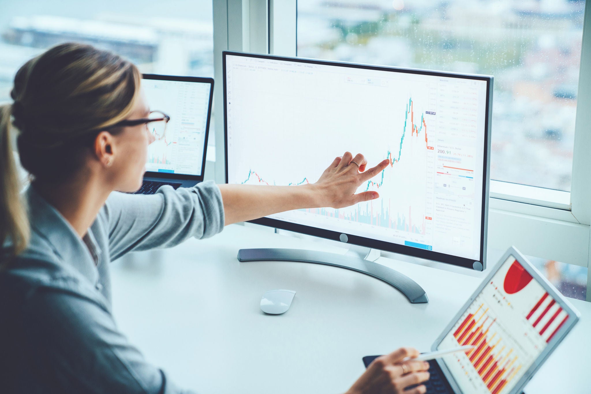  En forretningskvinne studerer finansmarkedet og ser på statistikkgrafer på dataskjermen og følger med på bytteavtaler.