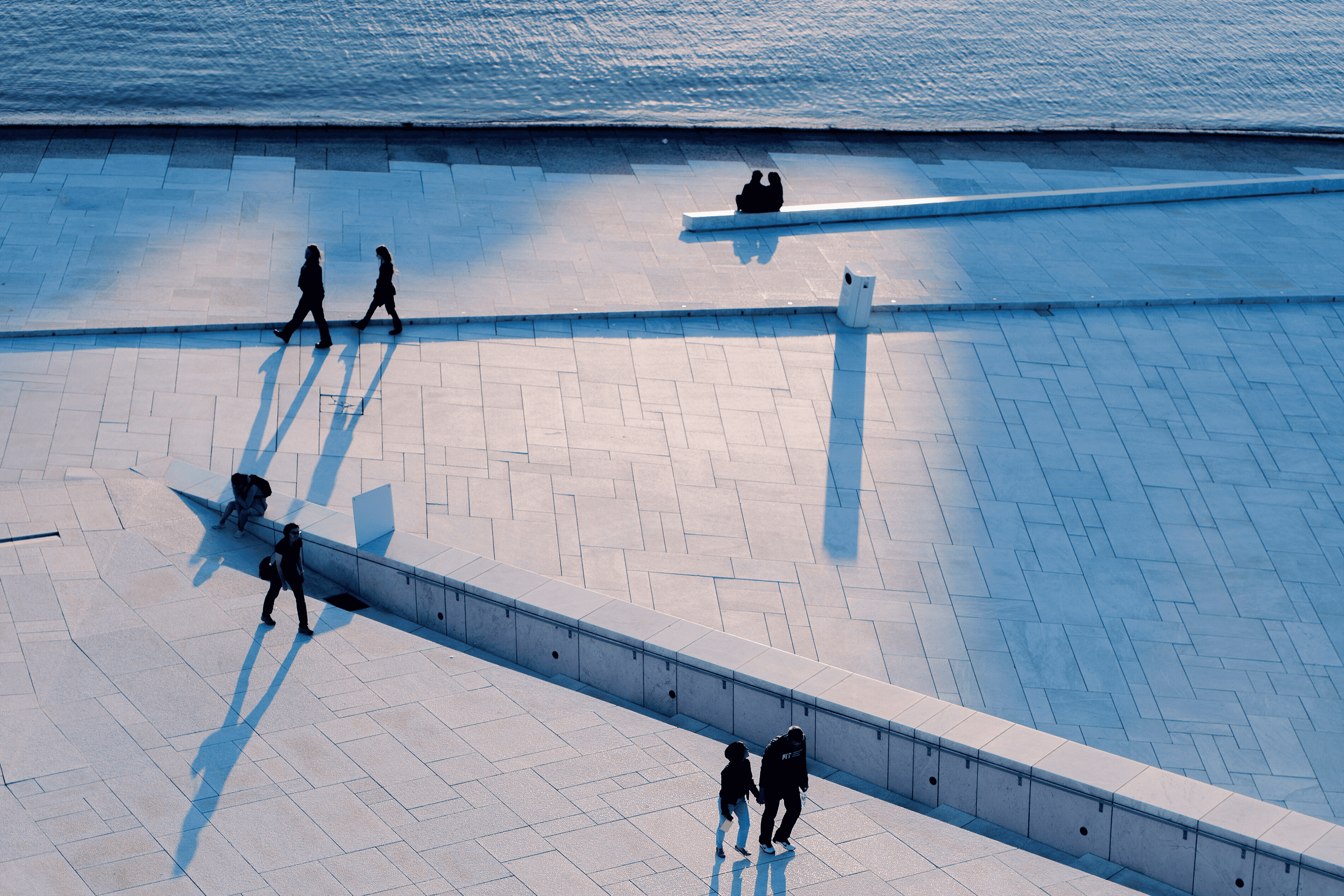 Mennesker som sitter og går oppover taket til Operaen i Oslo i solnedgang