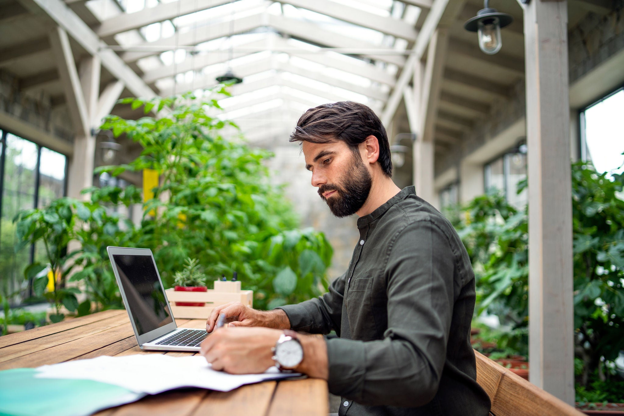 Mand arbejder ved computer i rum med planter