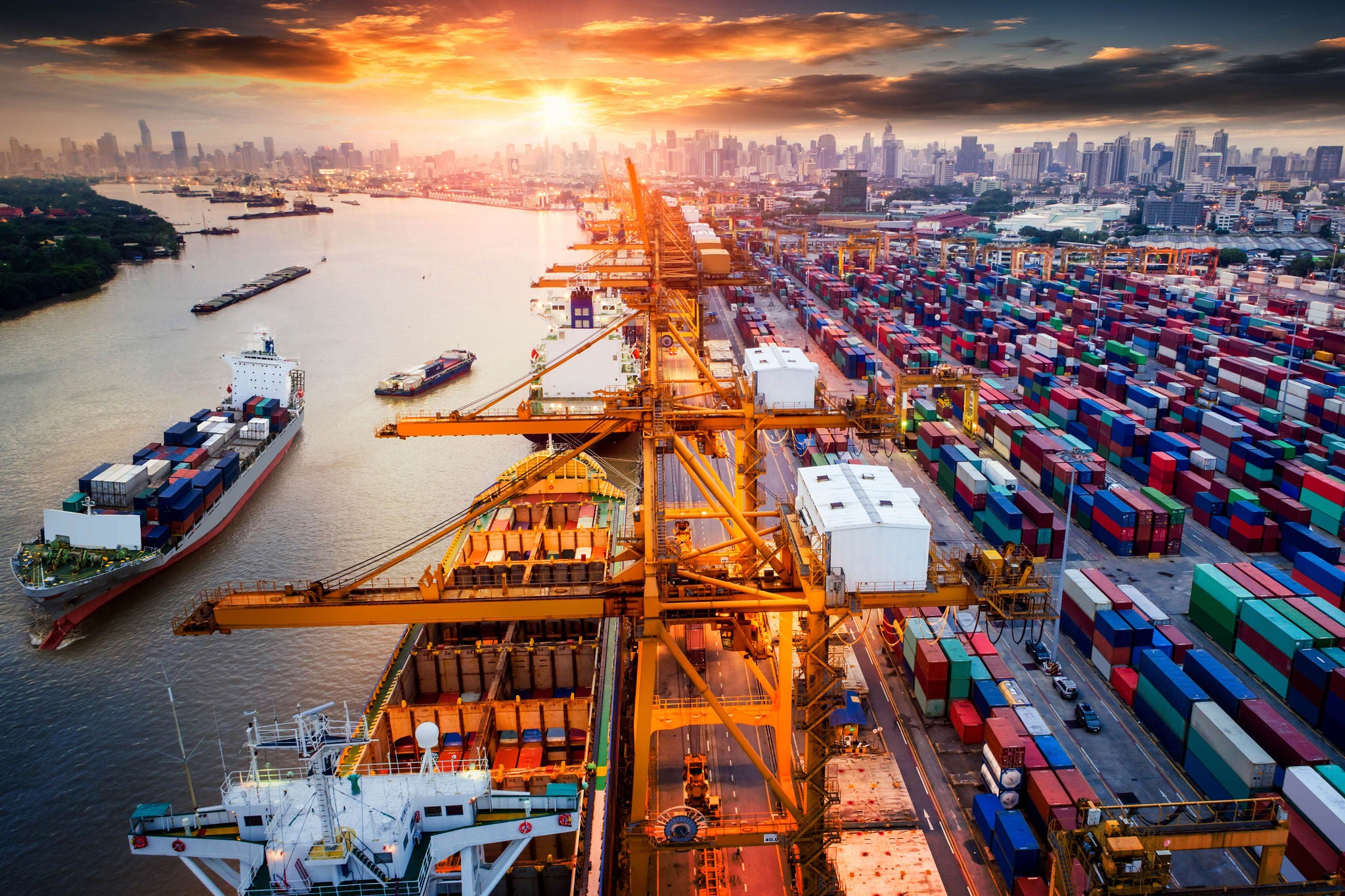 An aerial view of a busy port with cranes loading and unloading shipping containers from cargo ships