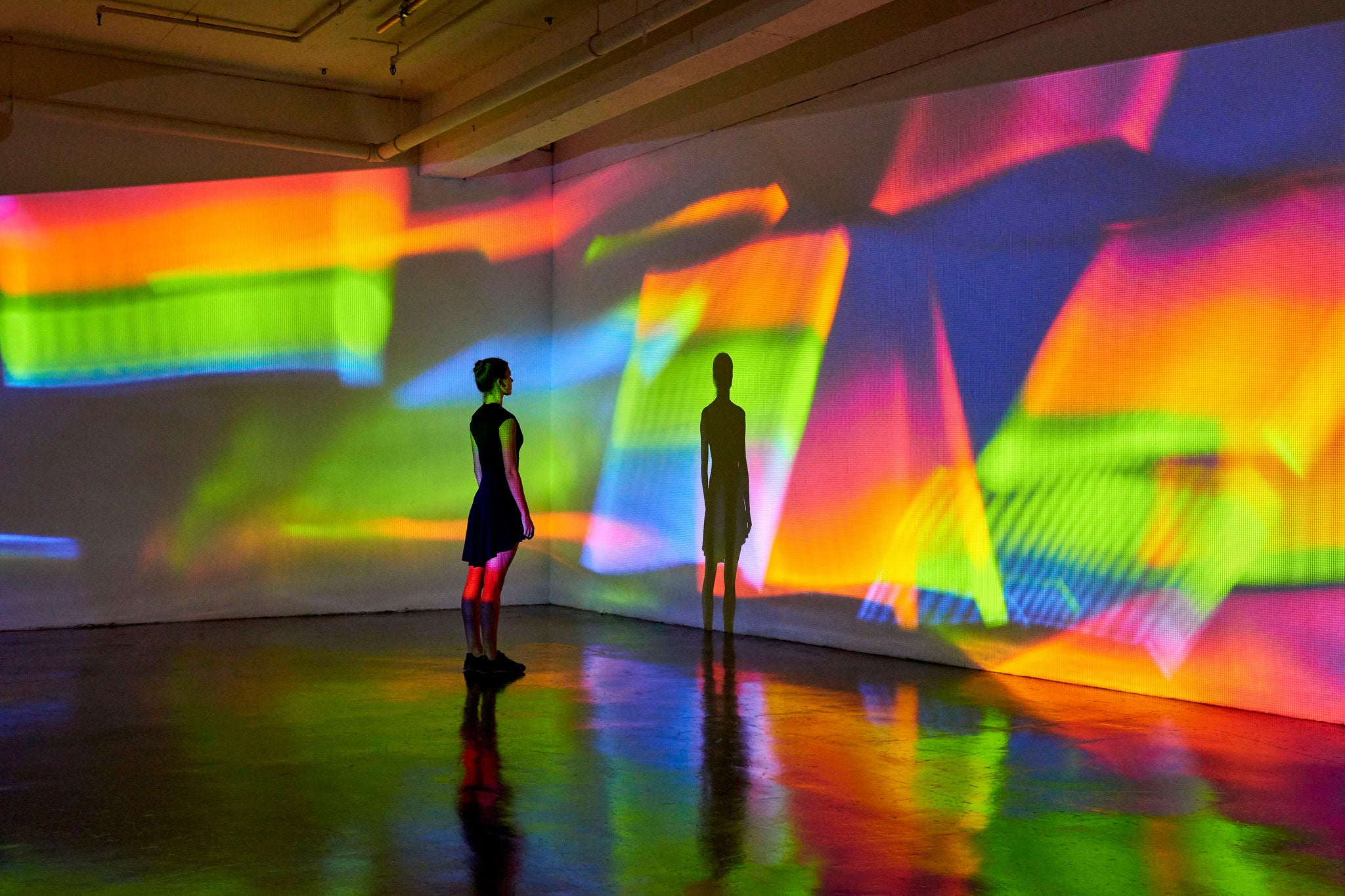 Girl looking at a large scale image of projected patterns in a gallery space