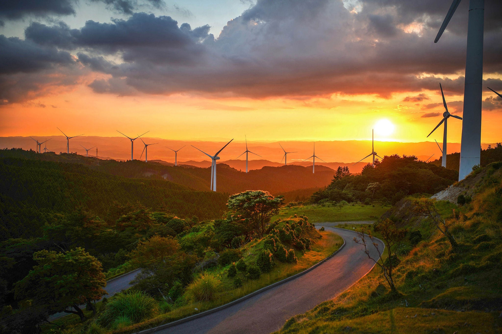 Windmills on field against cloudy sky