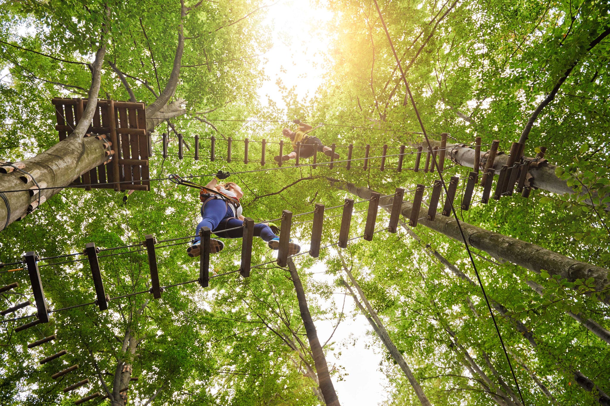 low angle view of three friends in adventure park climbing on suspension bridge.summer day.