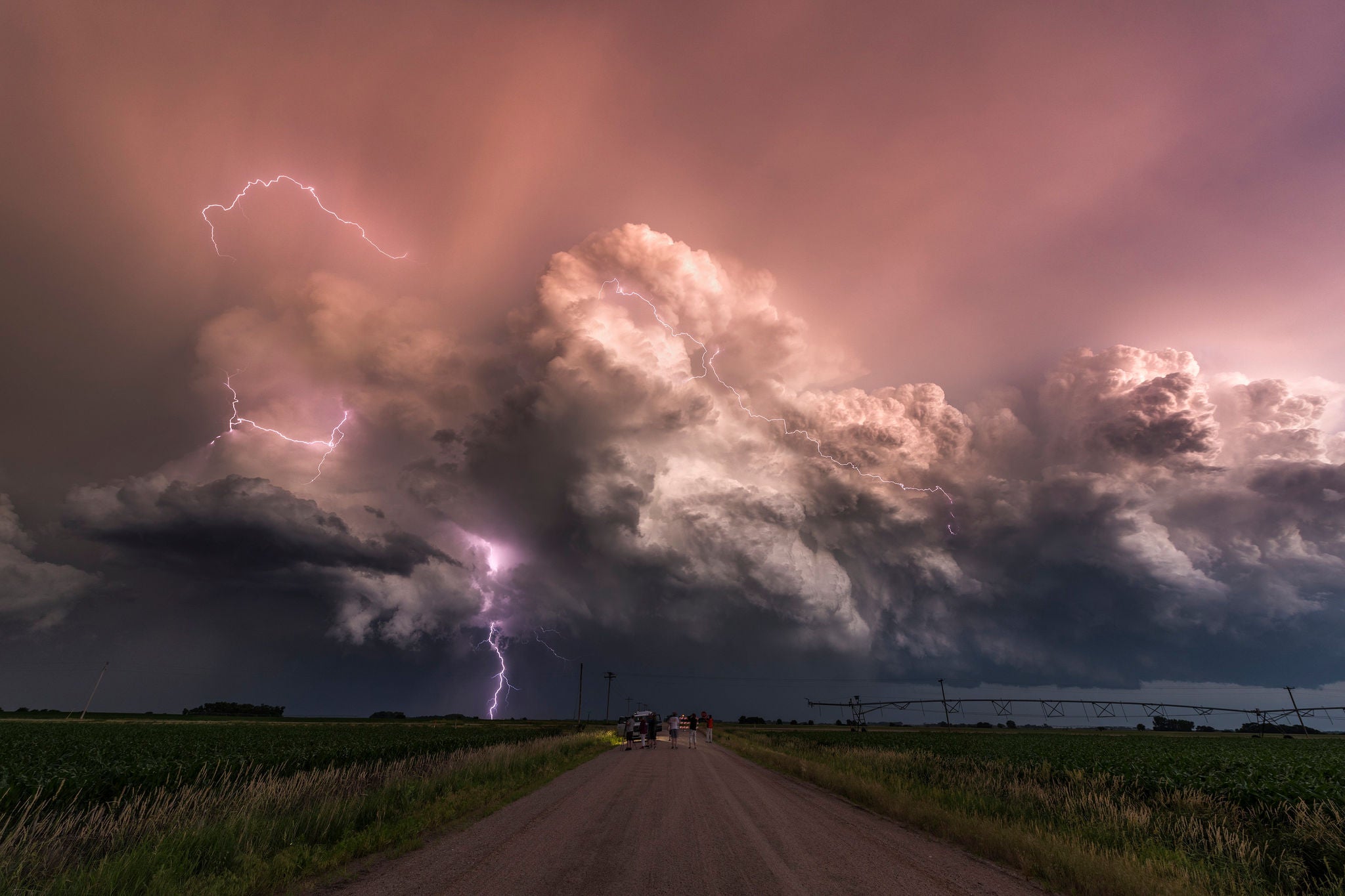 A group of storm chasers watch in amazement as one of the best electric storms of the season floats across farmland in Nebraska at sunset. USA