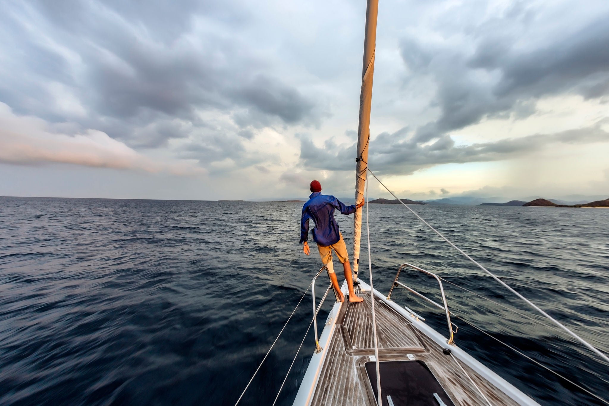 Rear view shot of single man standing on bow of yacht, Lombok, Indonesia