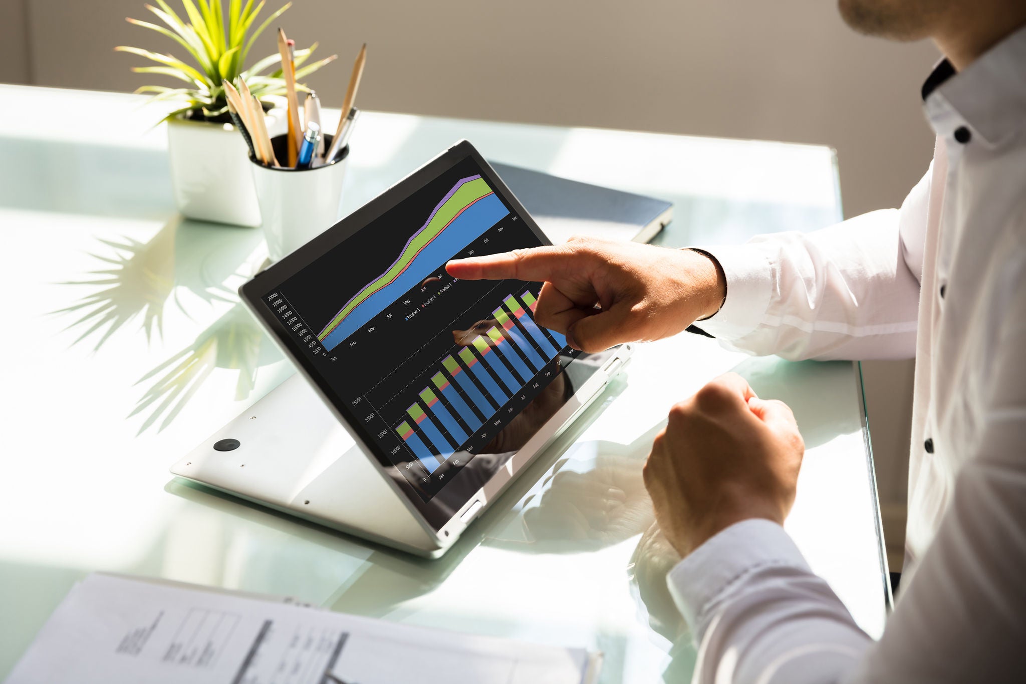 Close-up of a businessman's hand analyzing graph on laptop at workplace