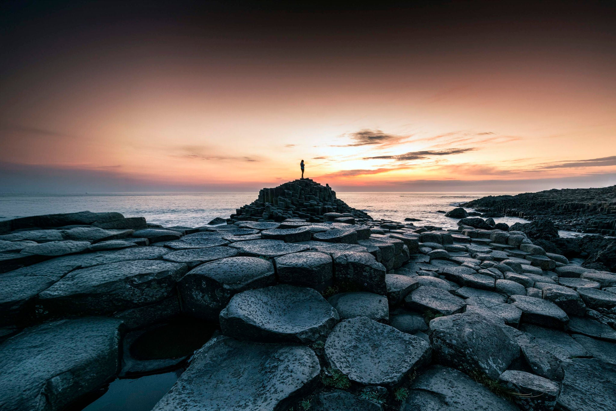 United Kingdom, Northern Ireland, County Antrim: silhouette of a person at the Giants causeway at sunset.