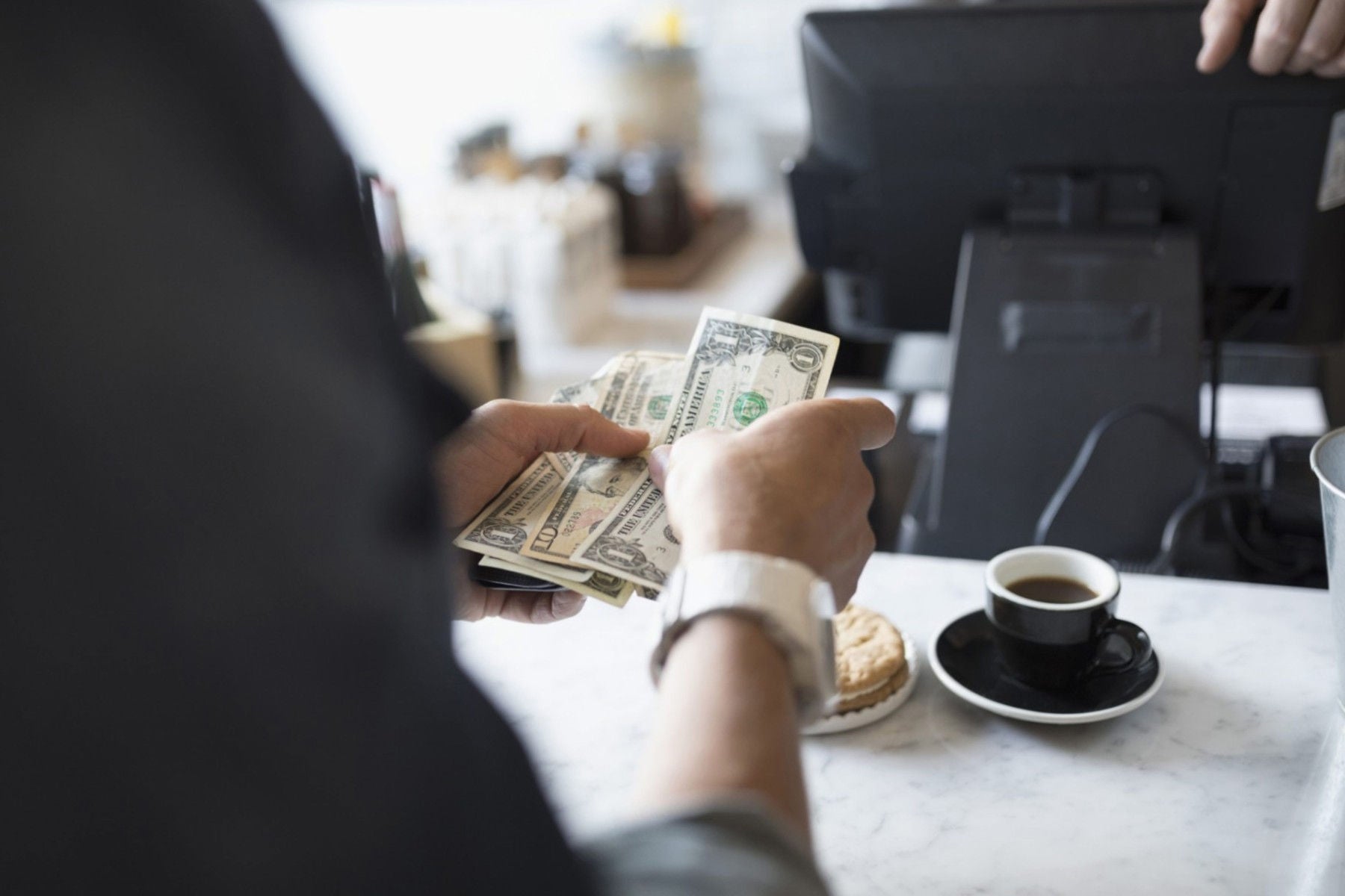 ey-man-holding-dollars-in-hand-at-a-coffee-shop