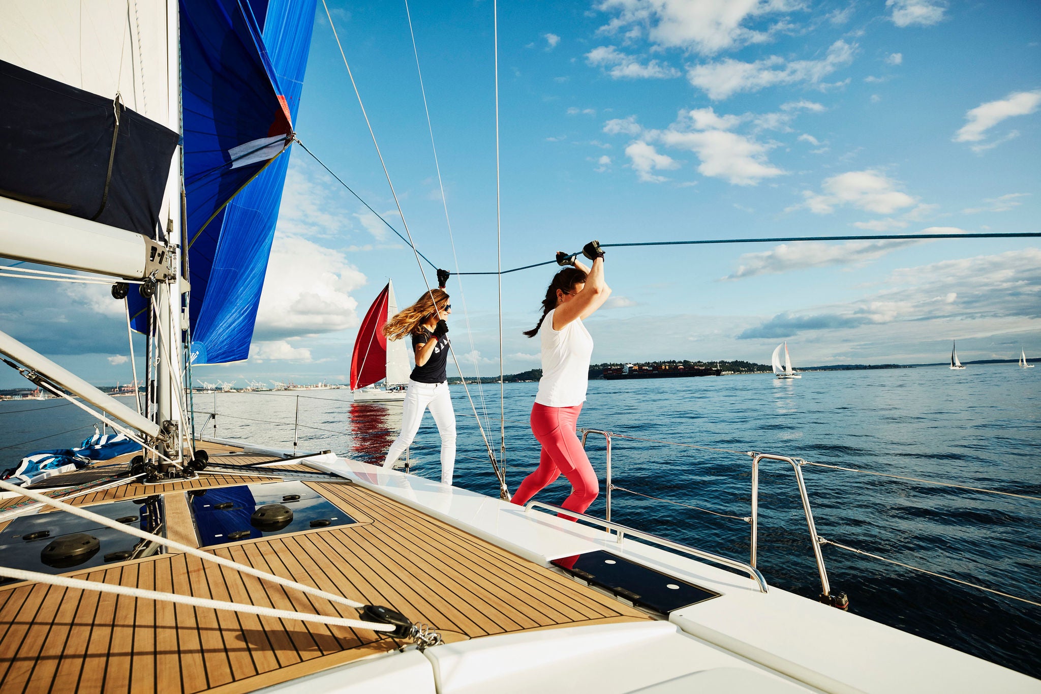 Female sailboat crewmembers trimming spinnaker during summer evening sail