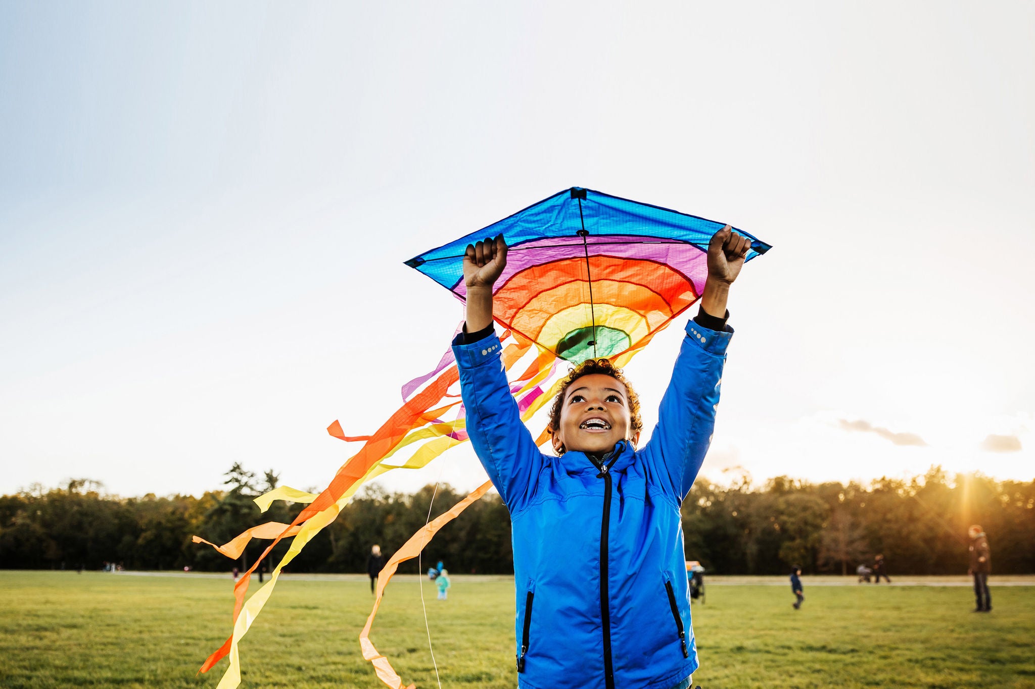 A young boy out in a park enjoying learning how to fly a kite.