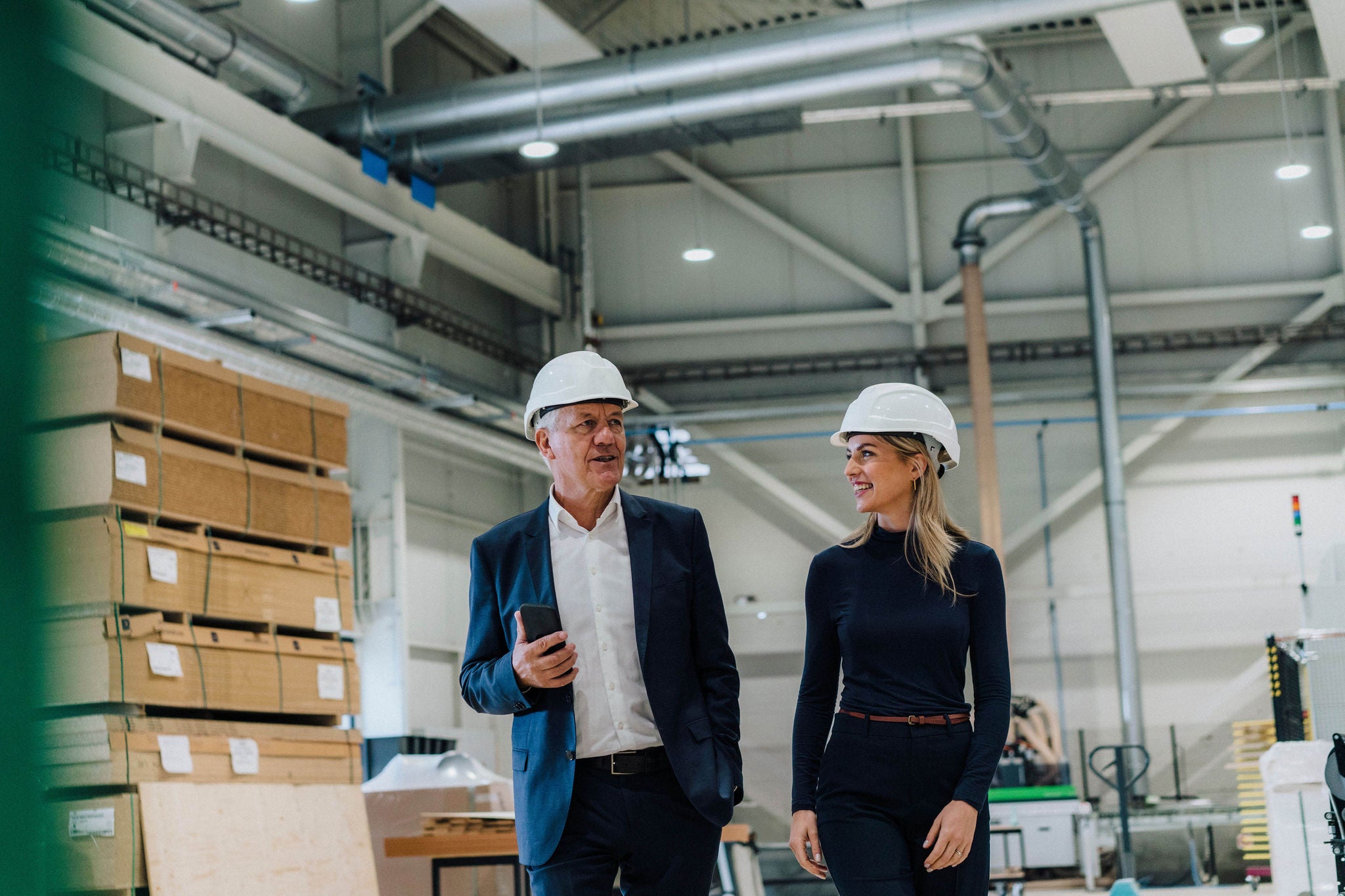 Senior businessman discussing with smiling colleague in carpentry factory