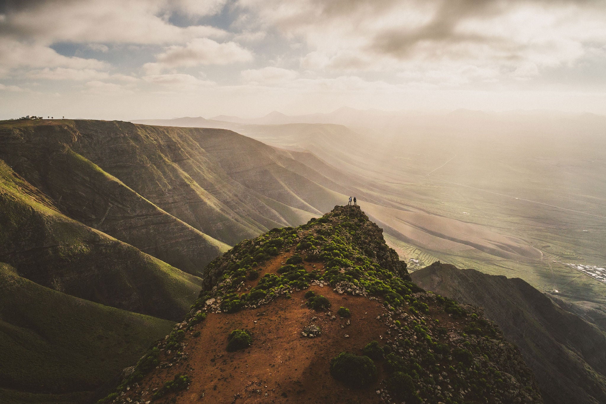  Two people standing at the edge of the hill top in nature