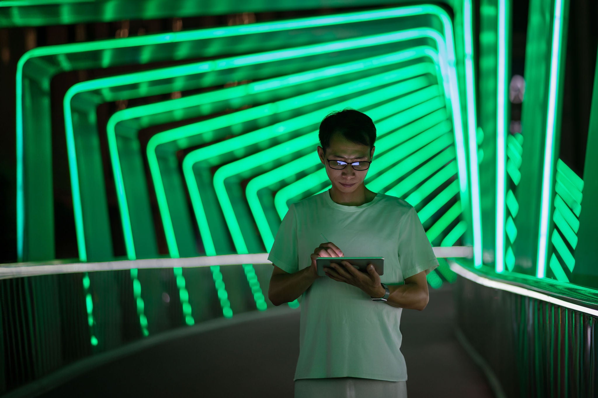 A man uses a tablet on a pedestrian bridge on Chuanggu Road, Tong'an District, Xiamen City, Fujian Province, China