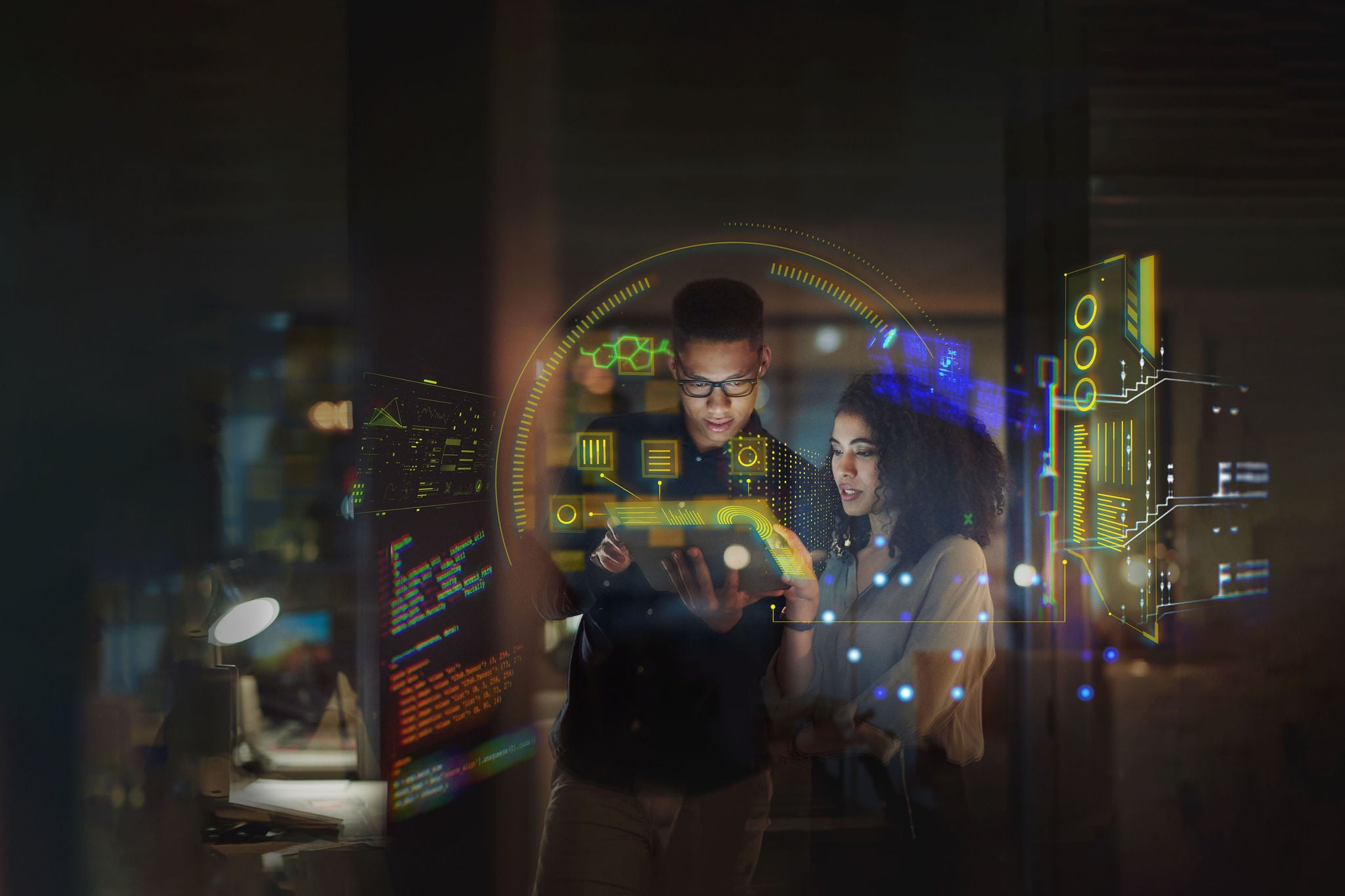 Shot of a young businessman and businesswoman using a digital tablet during a late night at work