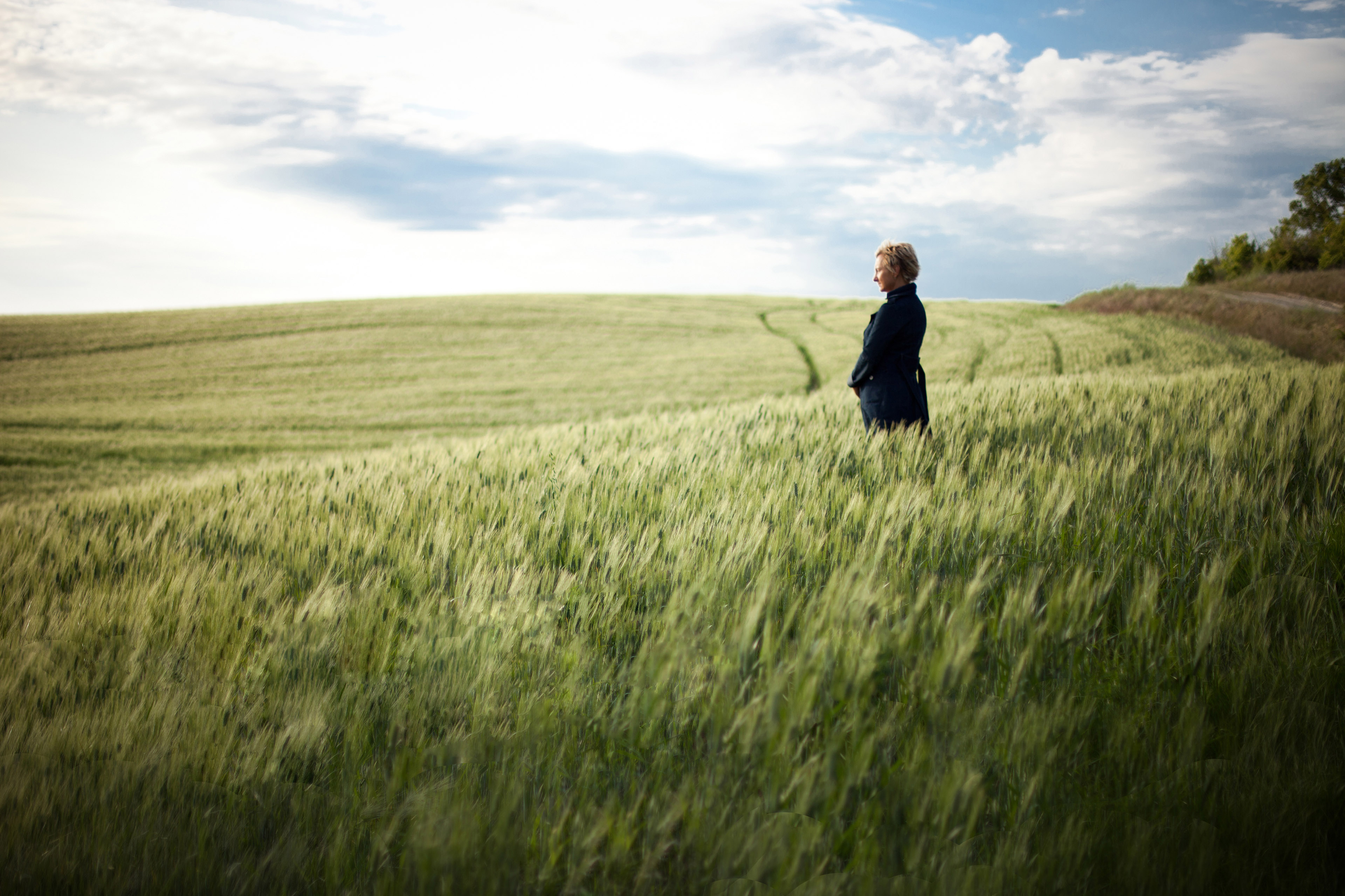 Woman in field of grain at sunset