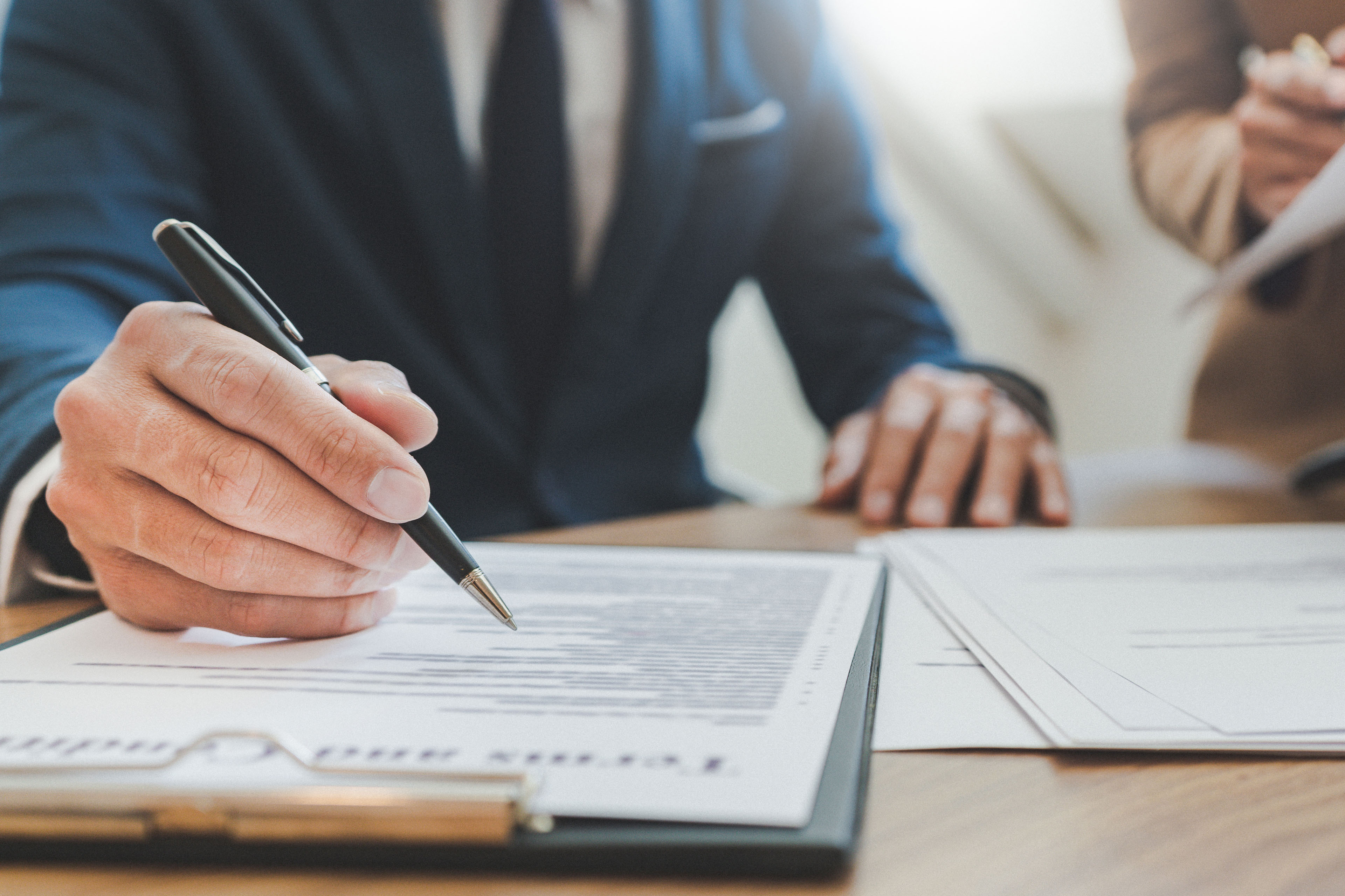 Midsection of male lawyer working with coworker on table hero