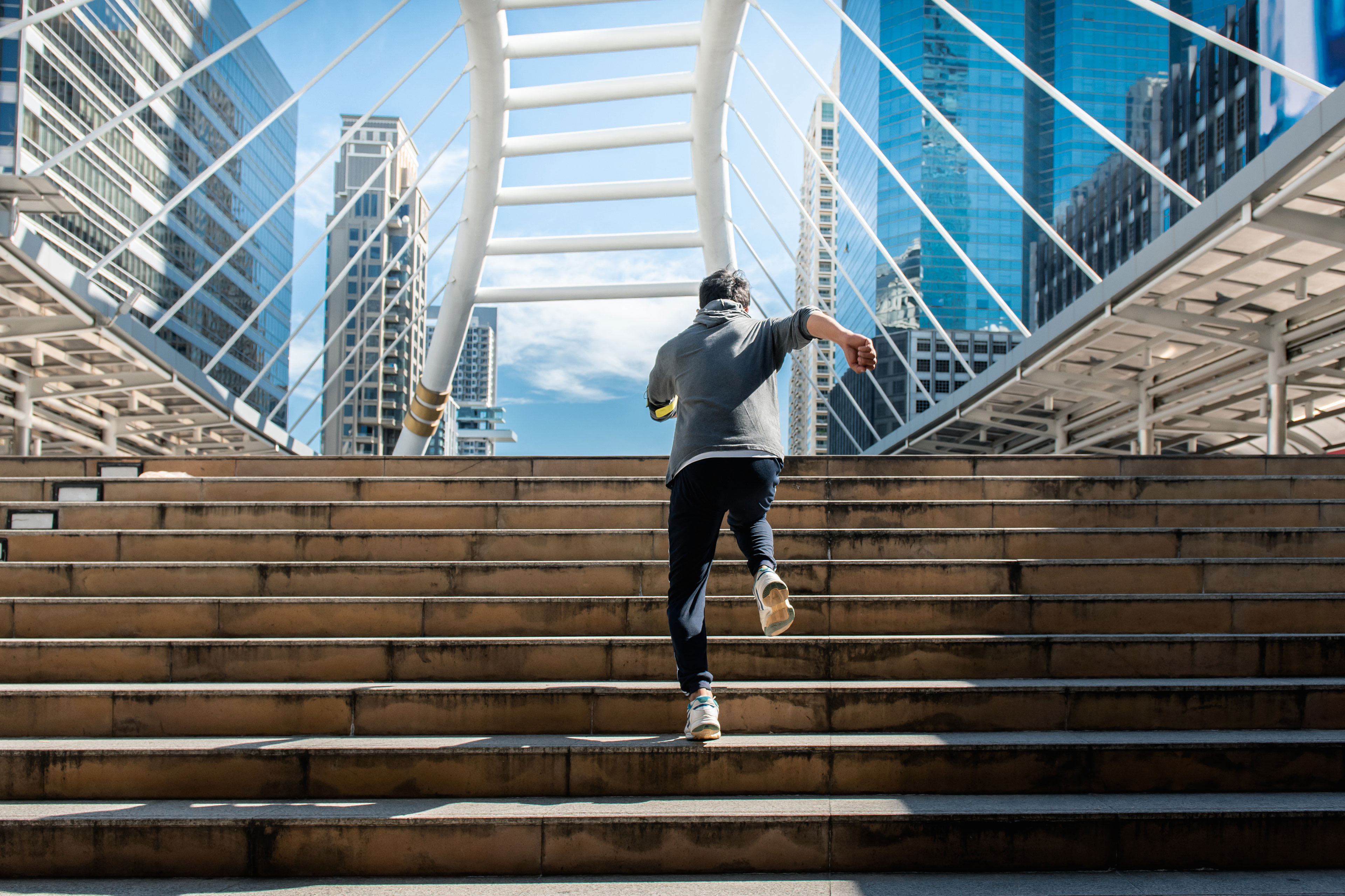 man running up stairs towards bridge