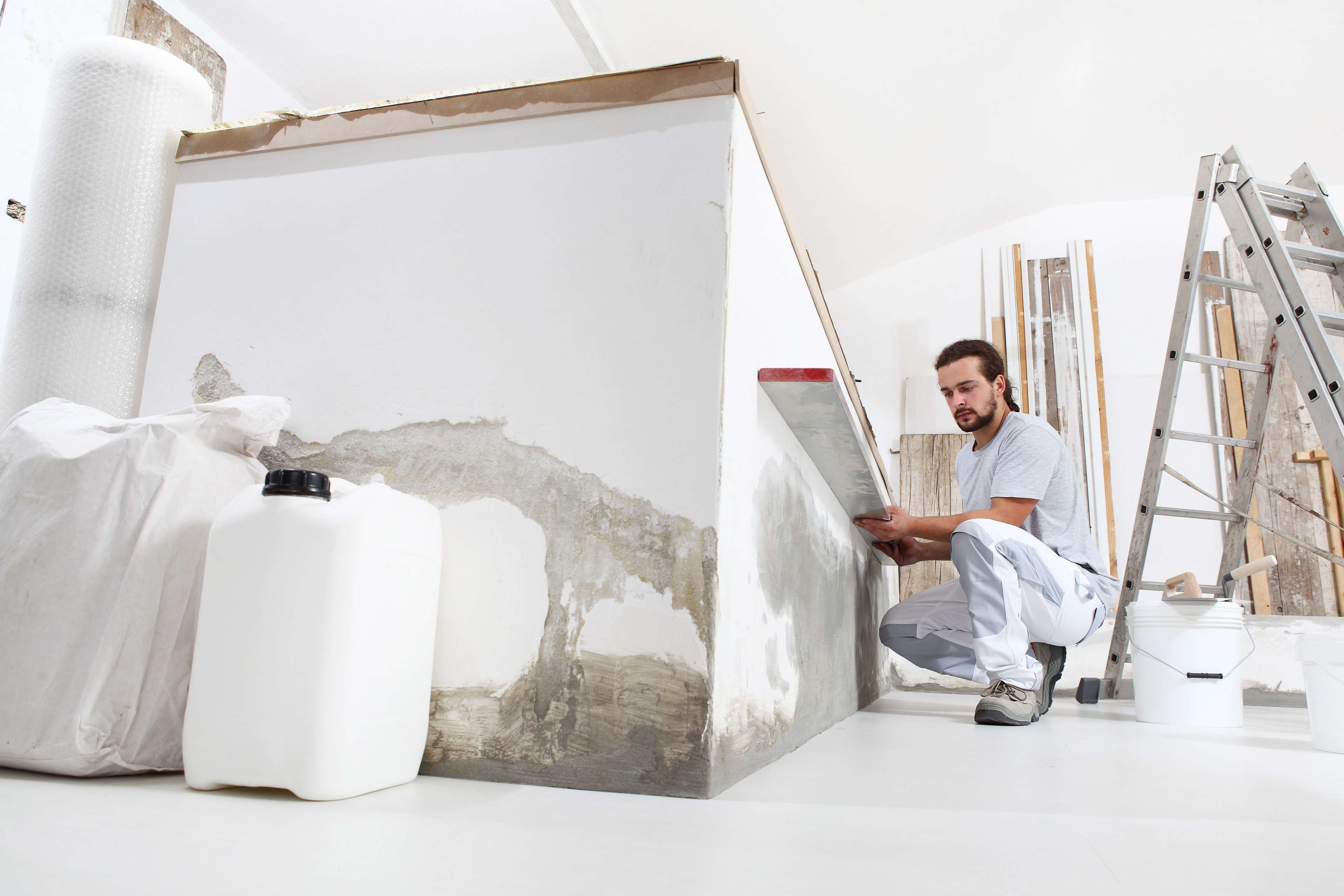 Bauarbeiter Stuckateur Mann schaut auf die Wasserwaage und prüft die Wand auf der Baustelle der  und Baumaterialie