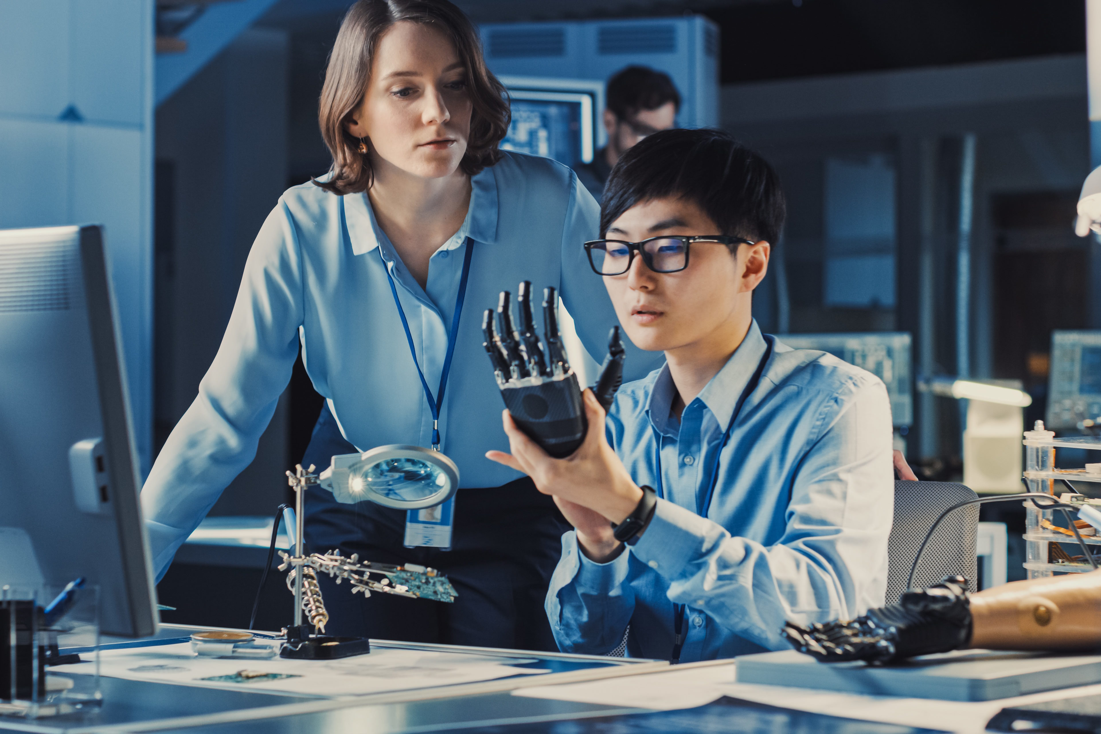 Two professionals looking at robotic arm