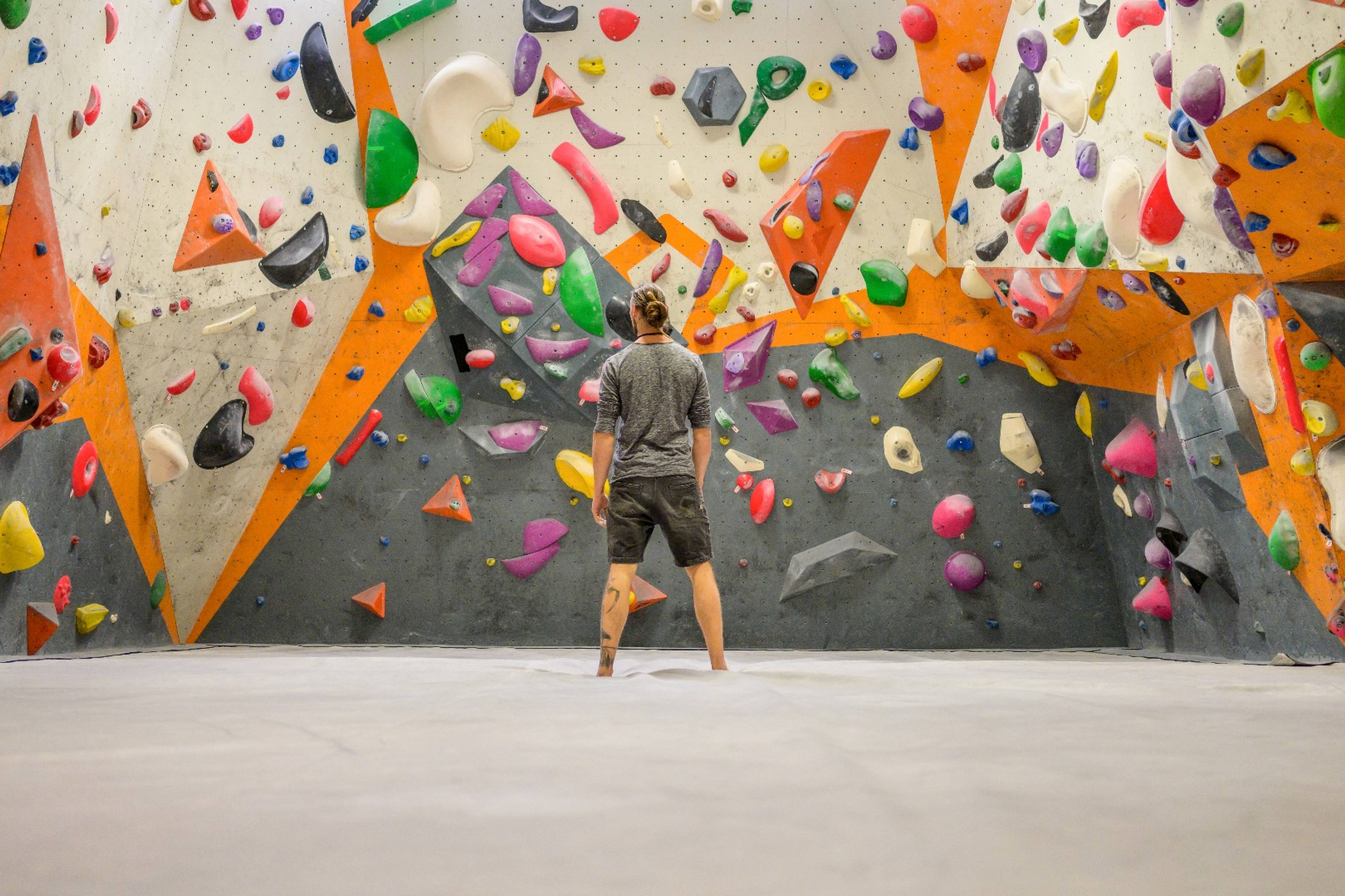 Man standing in front of an indoor rock climbing wall