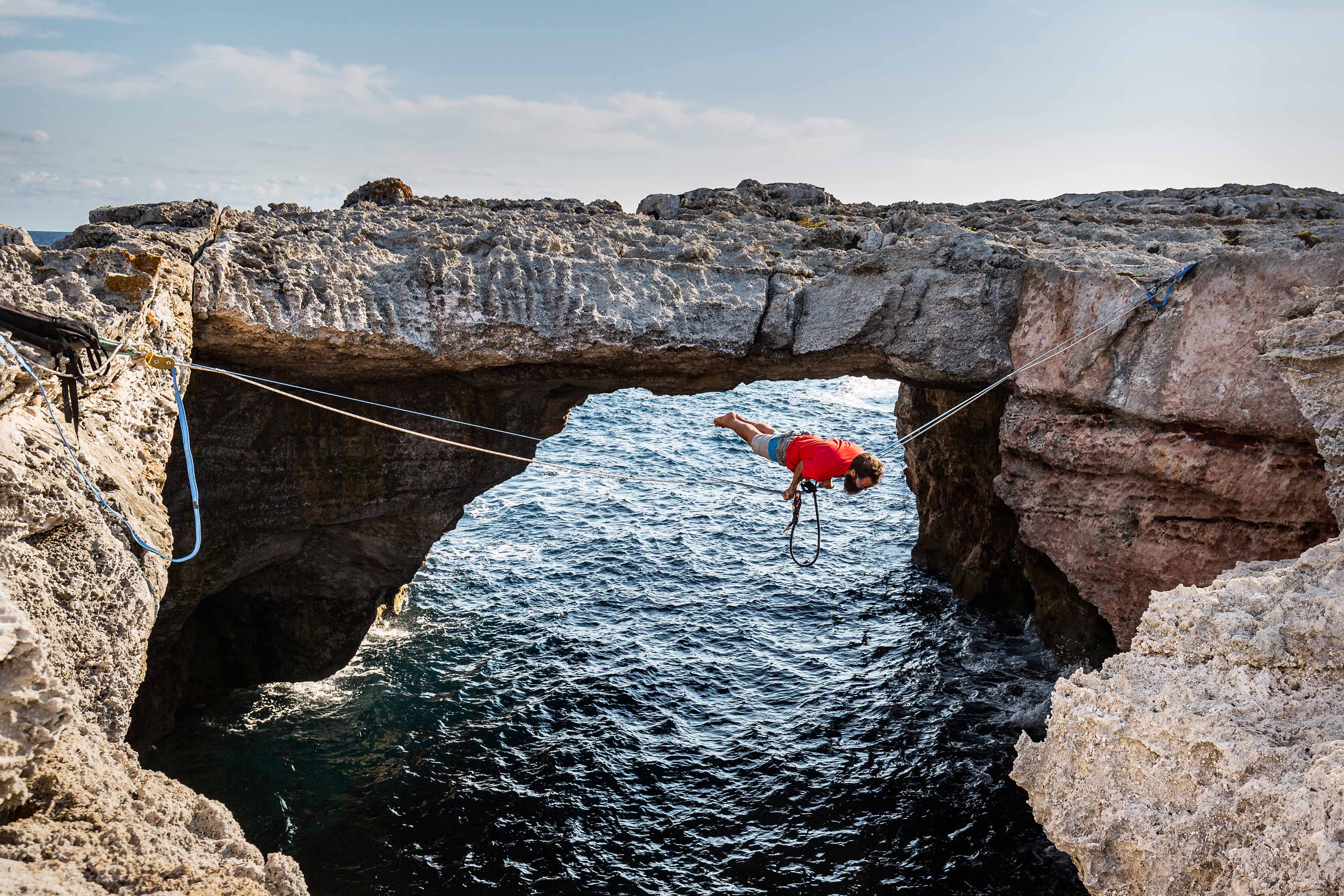 Man practicing slacklining over sea in minorca spain