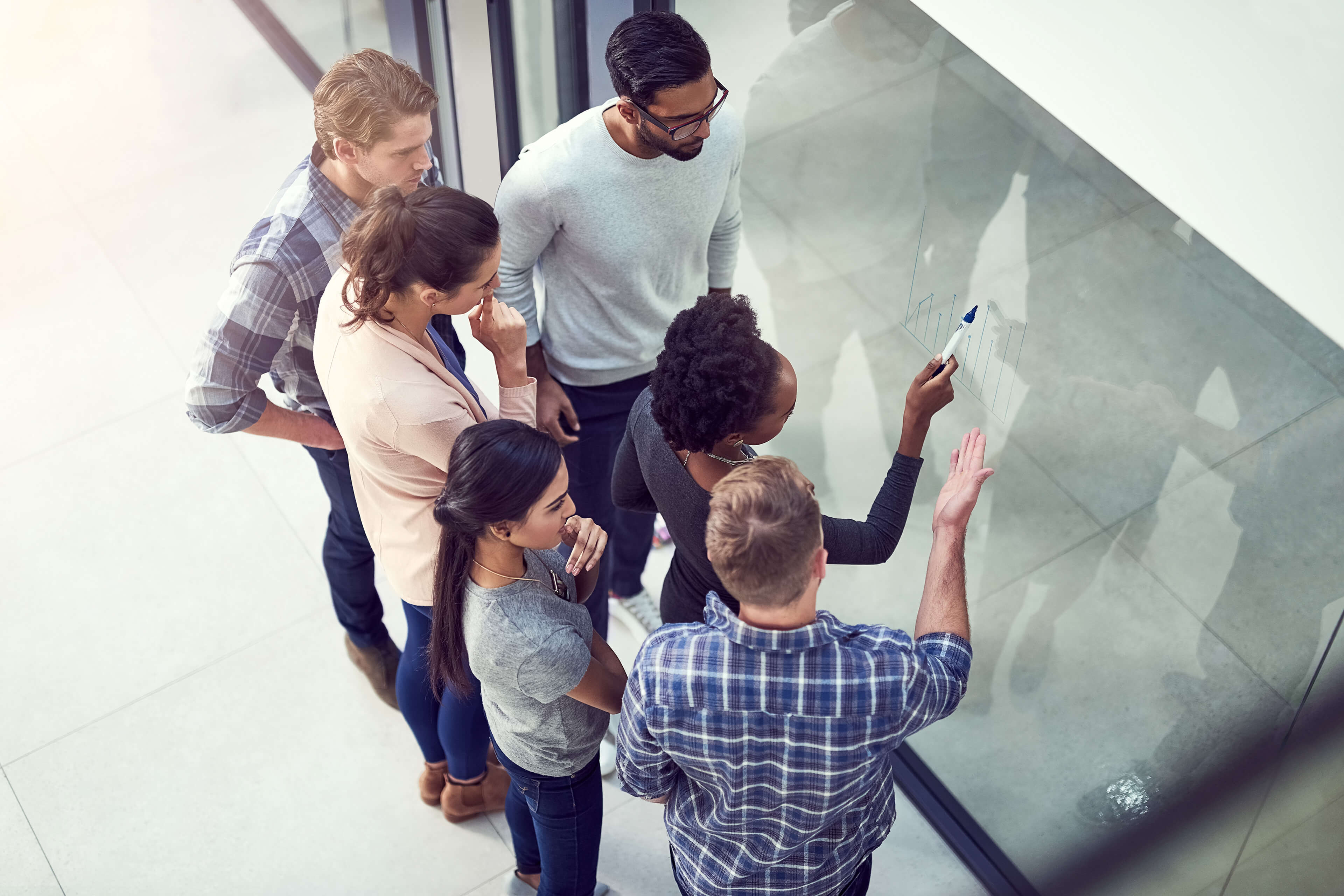 EY - Group of people looking at chart on window