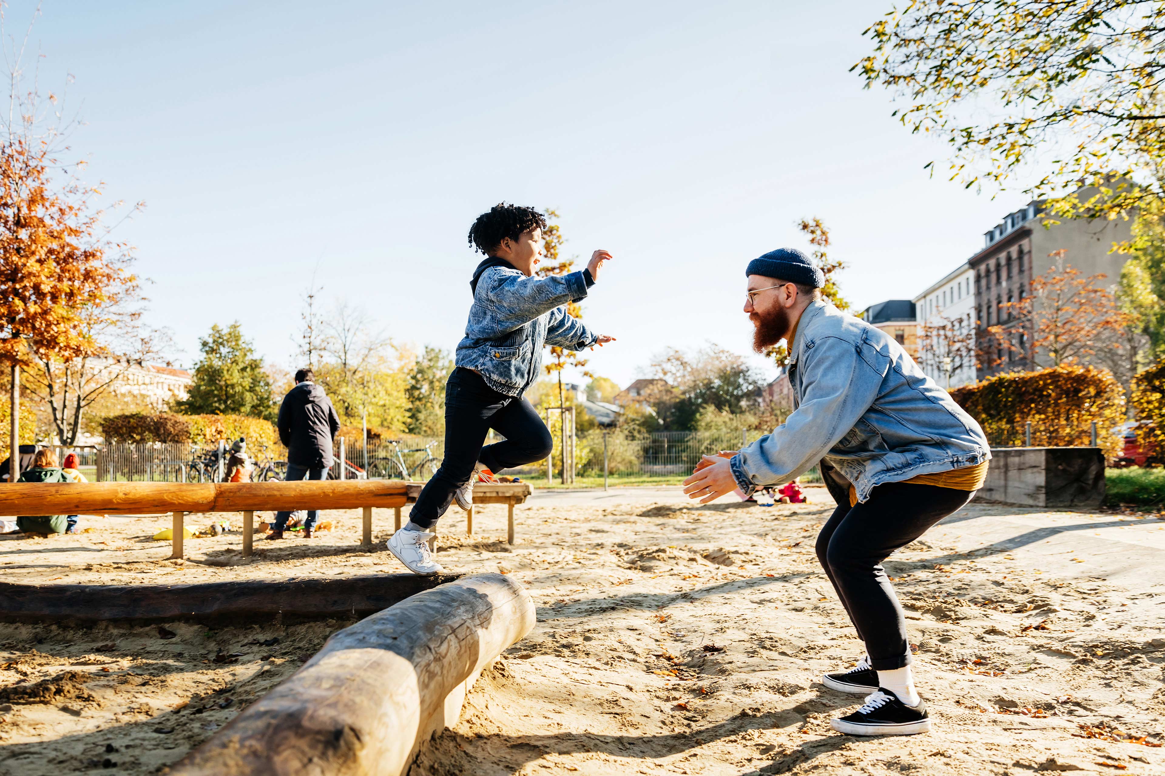 Young Boy Leaping Into Father Arms In Playground