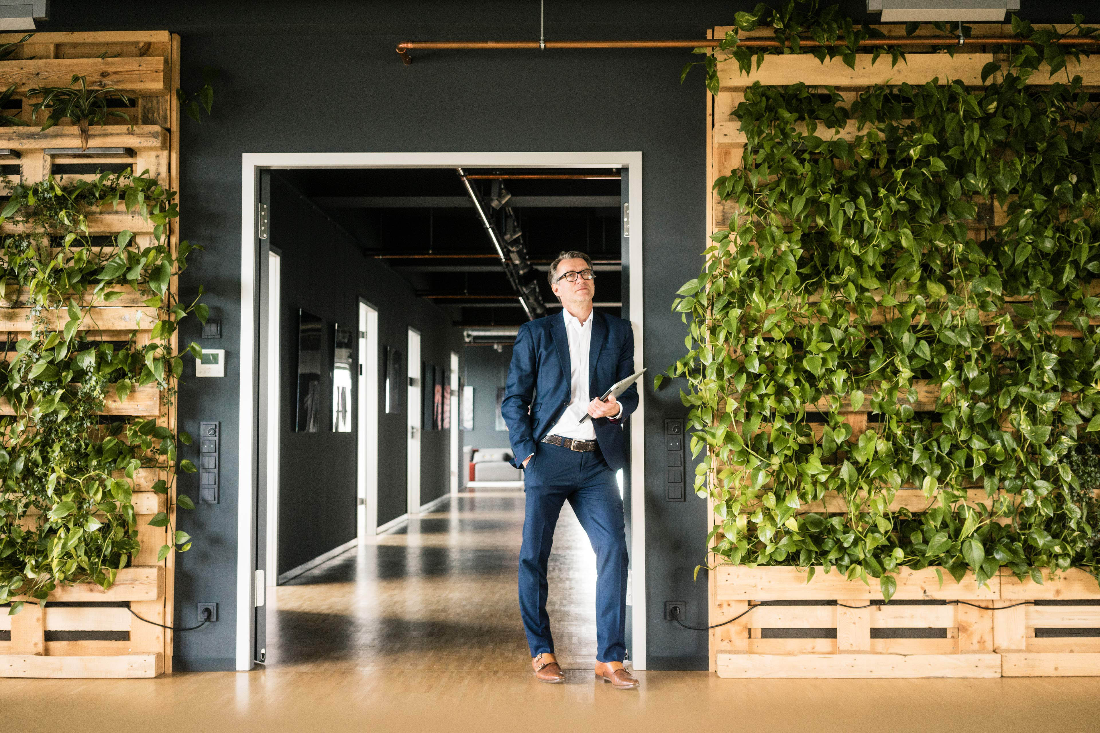 Mature businessman with laptop standing in green office