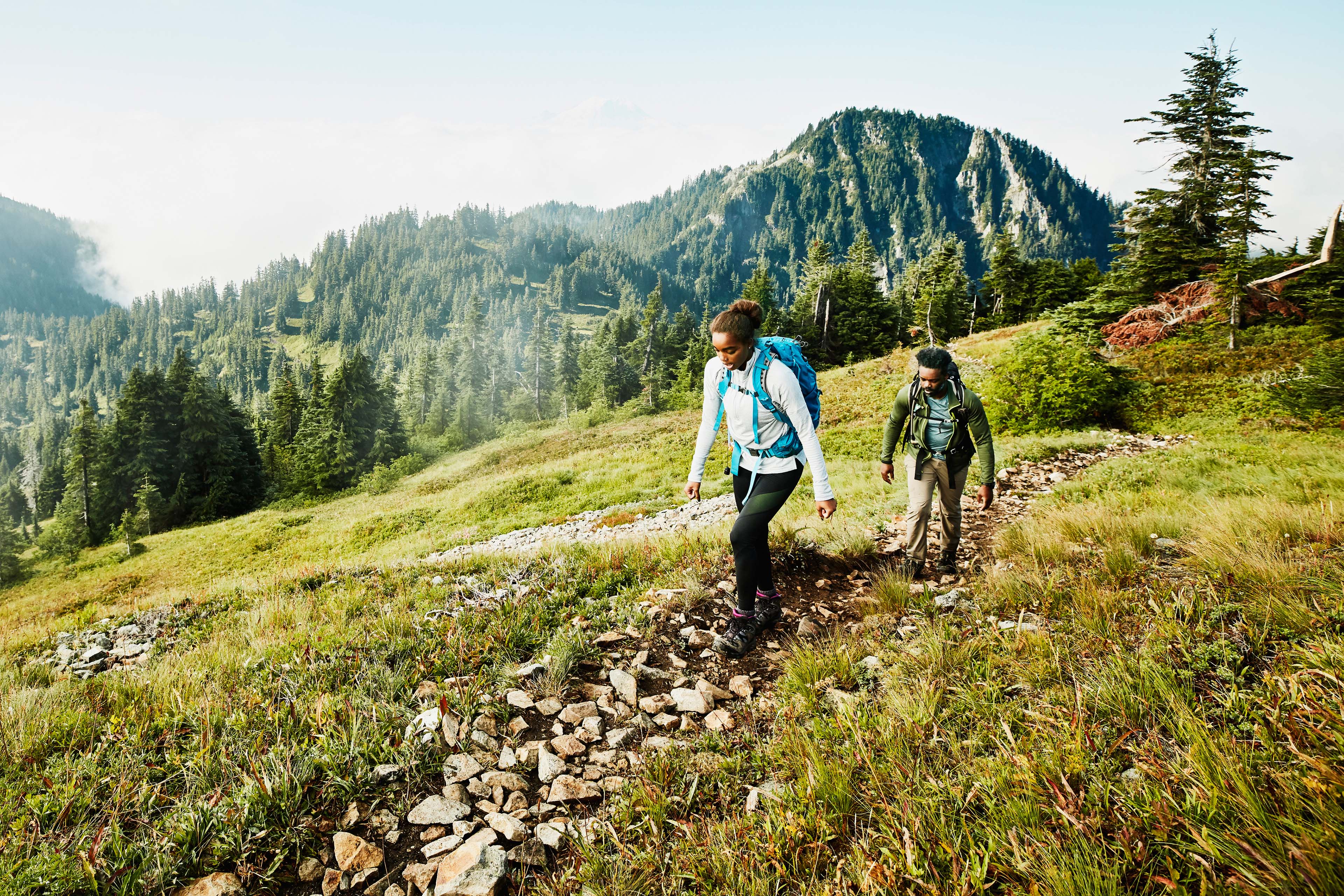 Daughter leading father on morning hike up mountainside