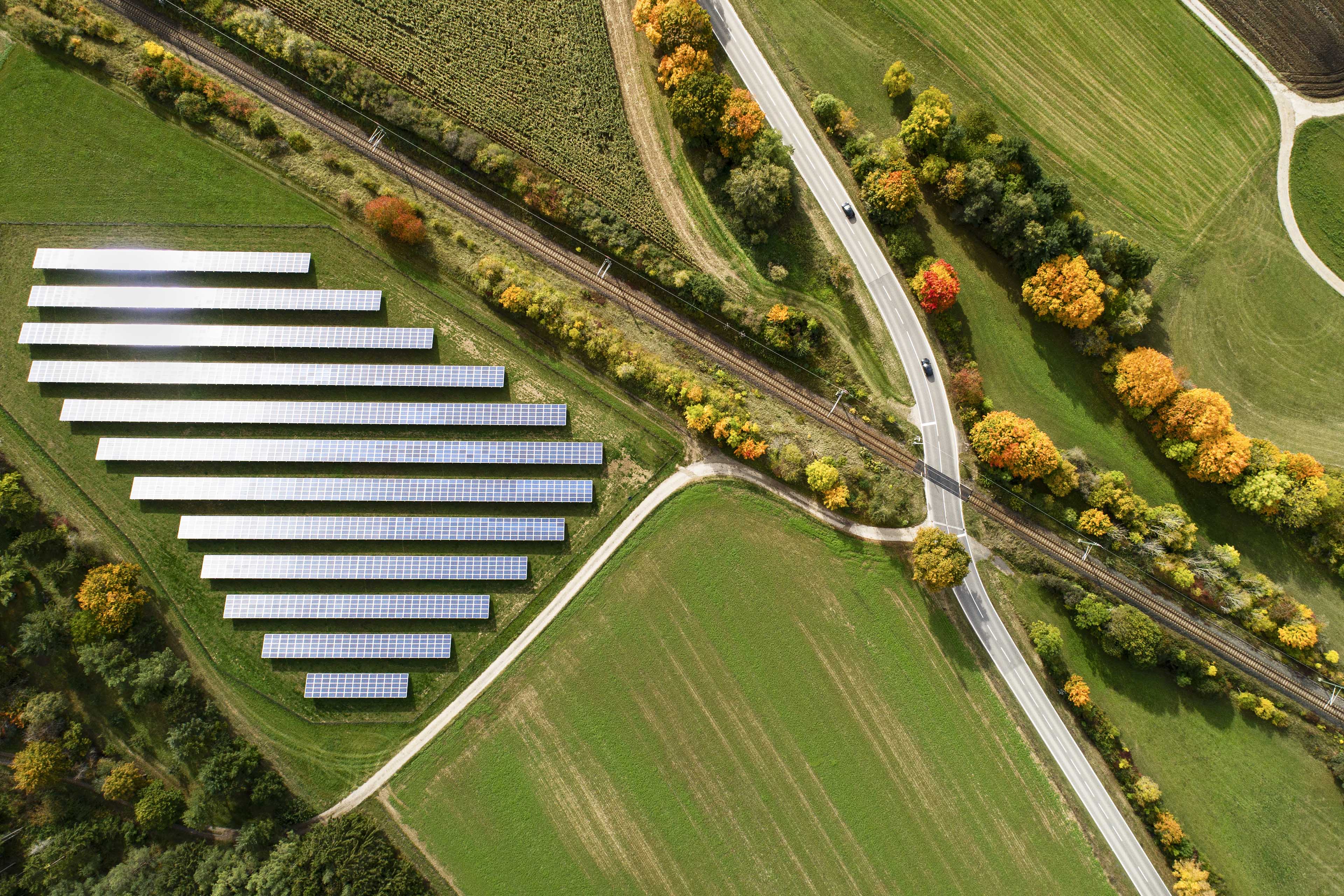 Aerial view of a highway crossing railroad tracks in Autumn , solar panels